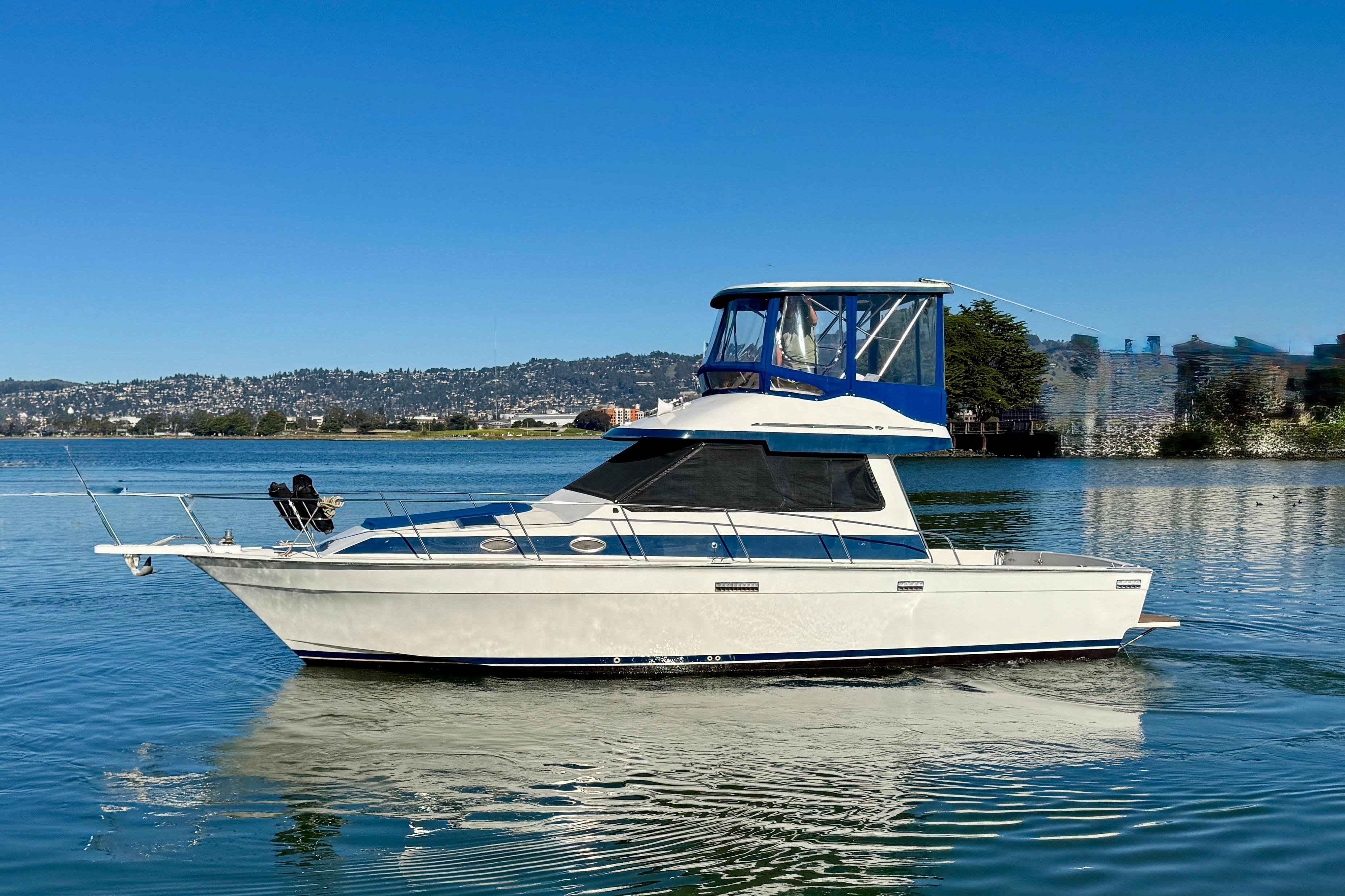 1989 Mediterranean 38 boat cruising on a calm lake under clear blue skies.
