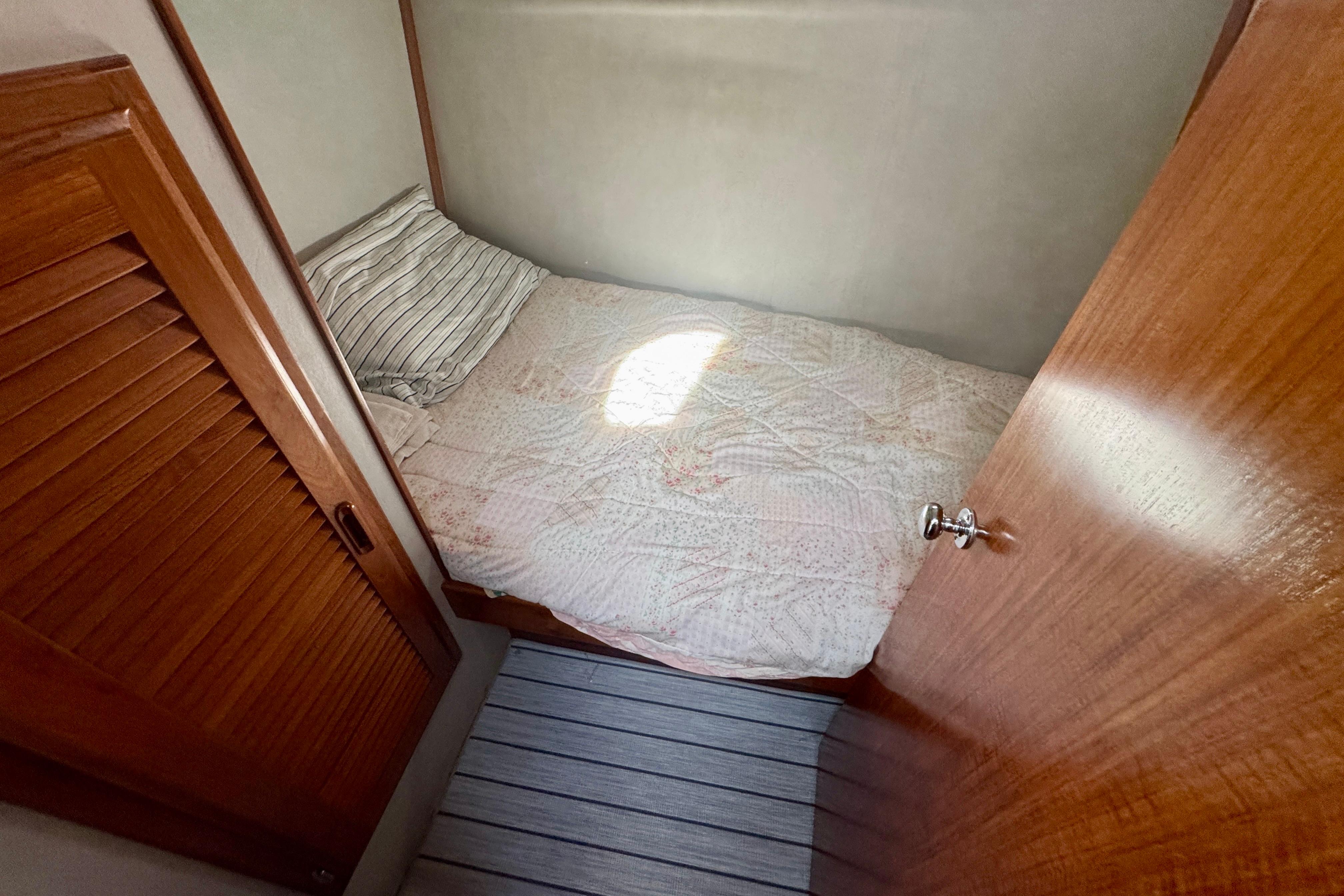 Cozy cabin bed in 1989 Mediterranean 38 yacht with wooden accents and striped pillow.