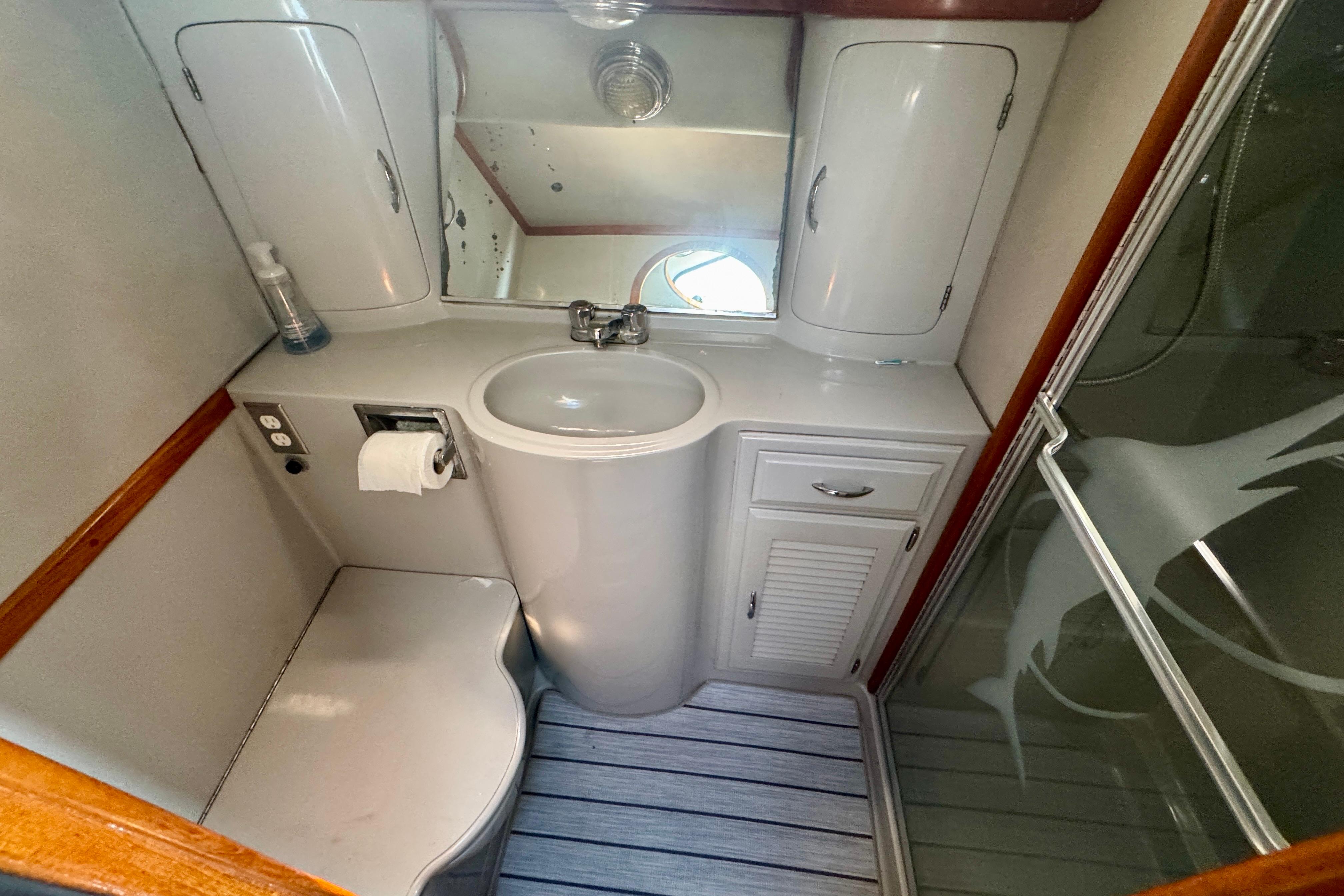Compact bathroom in a 1989 Mediterranean 38 yacht, featuring sink, mirror, and shower.