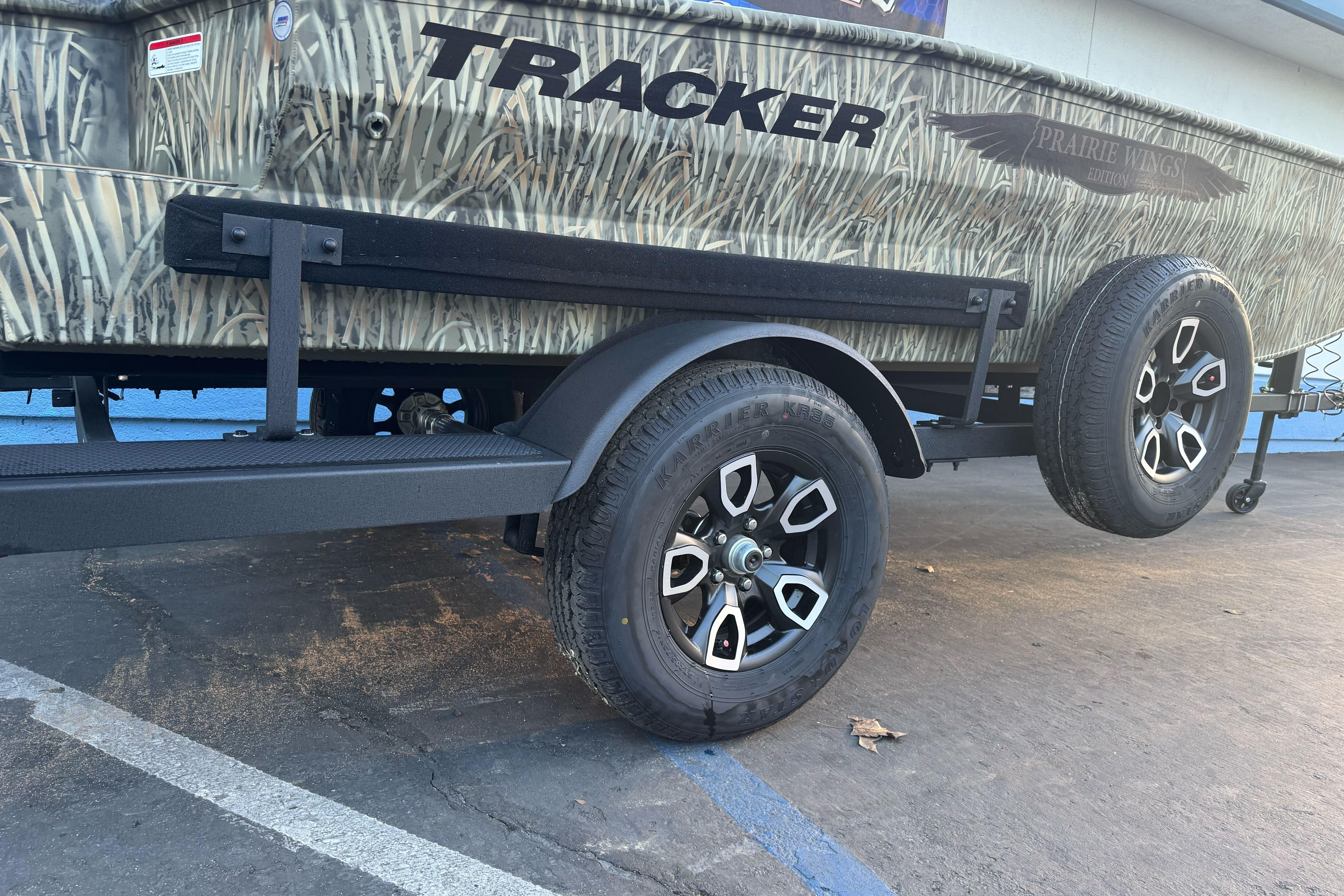 2026 Tracker Grizzly 1650 T Prairie Wings Edition trailer with camouflage design and black wheels.