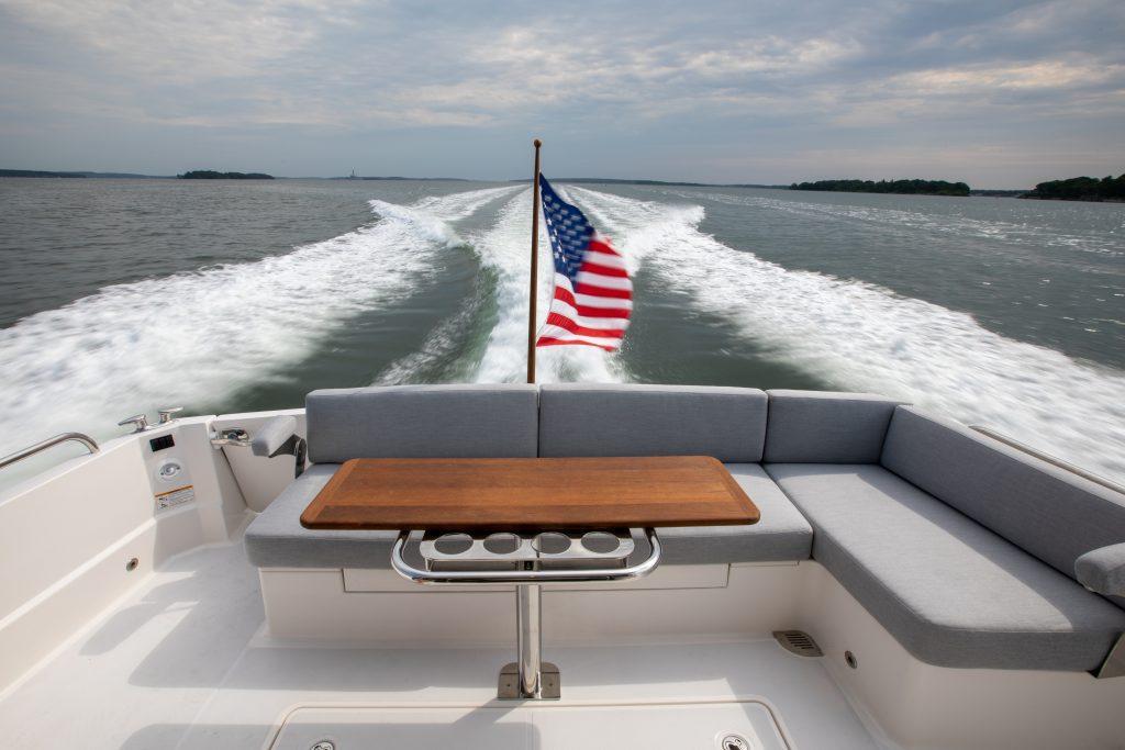2026 Sabre 43 Salon Express cruising with American flag, spacious seating, and ocean view.