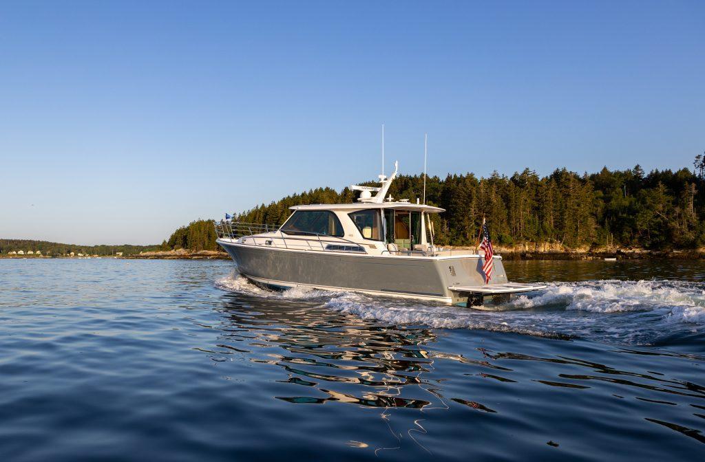 2026 Sabre 43 Salon Express cruising on a serene lake with forested shoreline.