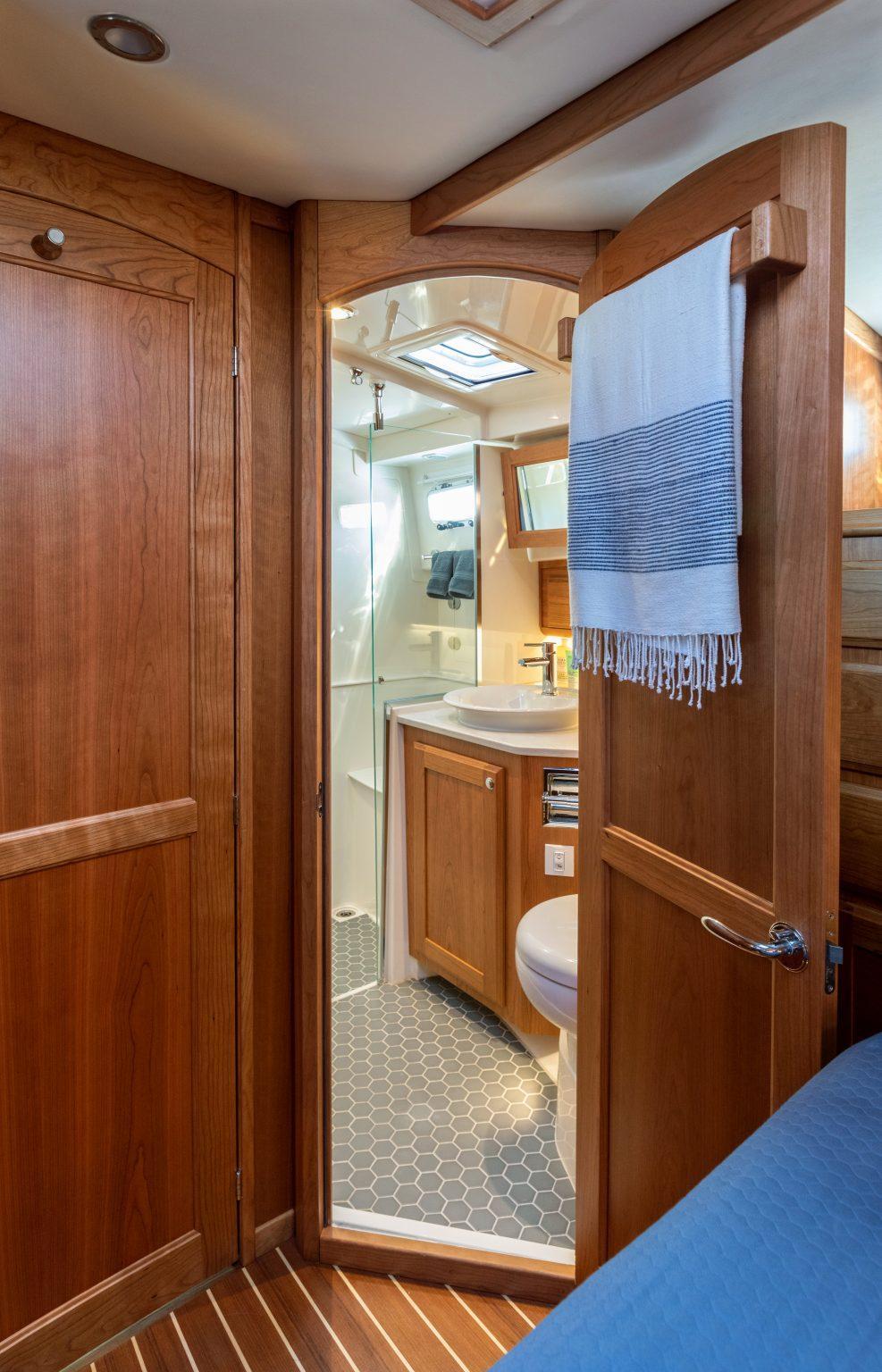 2026 Sabre 43 Salon Express yacht bathroom with wooden cabinetry and hexagonal tile flooring.