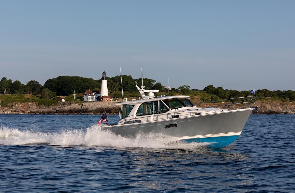 2026 Sabre 43 Salon Express cruising near a scenic lighthouse and rocky shoreline.