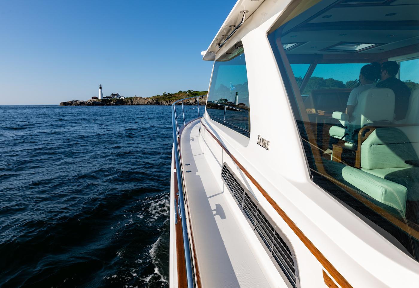 2026 Sabre 43 Salon Express yacht cruising near a coastal lighthouse.