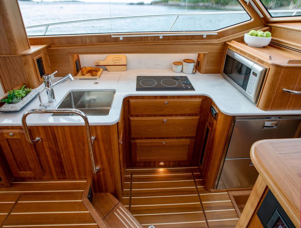 Luxurious kitchen interior of 2026 Sabre 43 Salon Express yacht with wooden cabinetry.