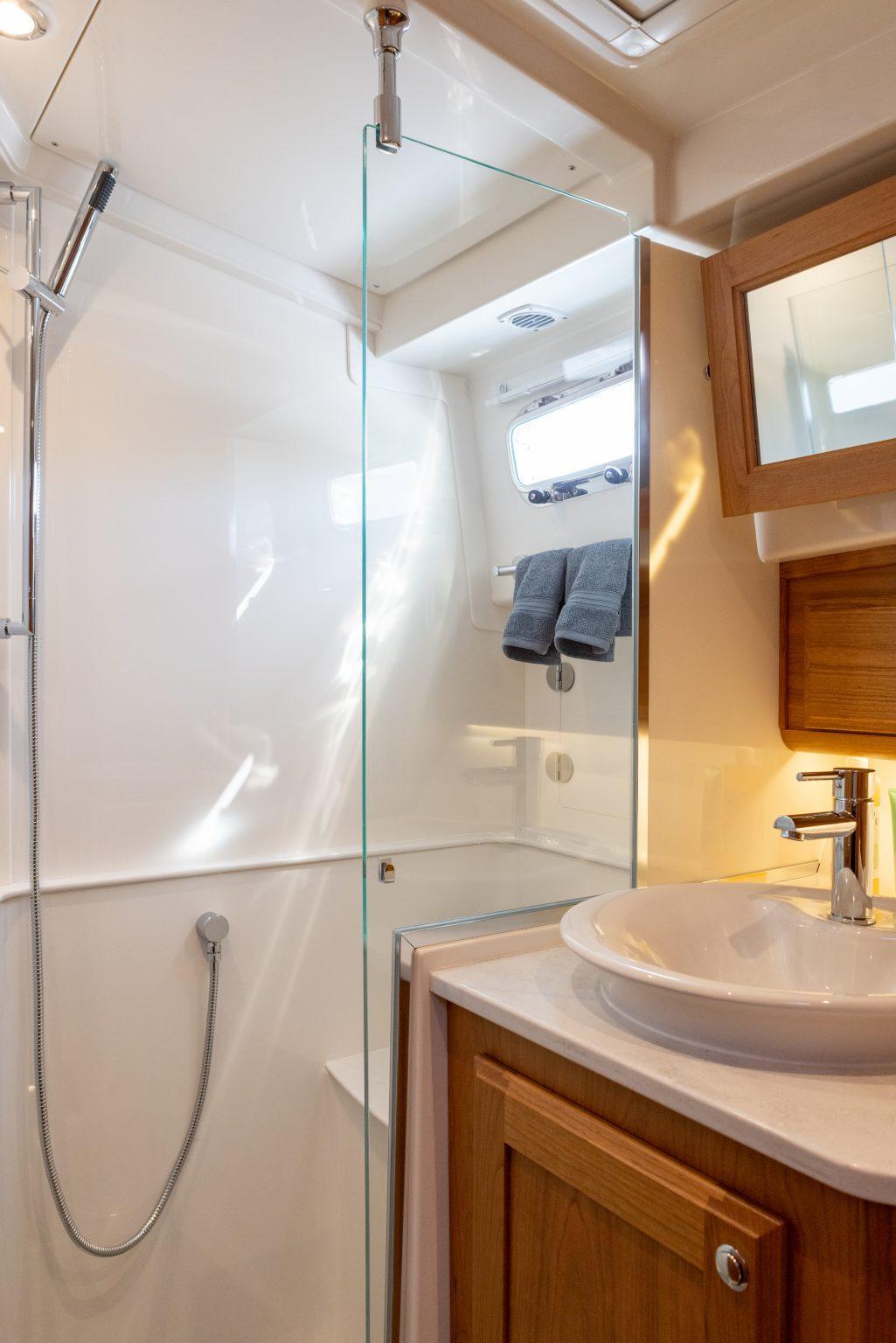 Modern bathroom in 2026 Sabre 43 Salon Express yacht with glass shower and wooden cabinetry.