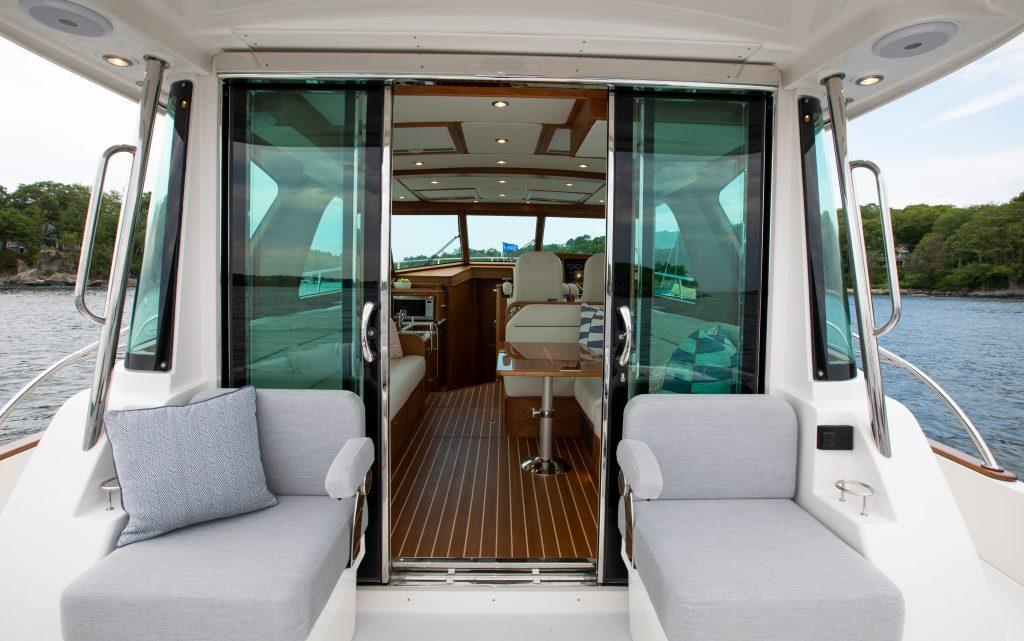 2026 Sabre 43 Salon Express yacht interior with seating and glass doors, overlooking water.