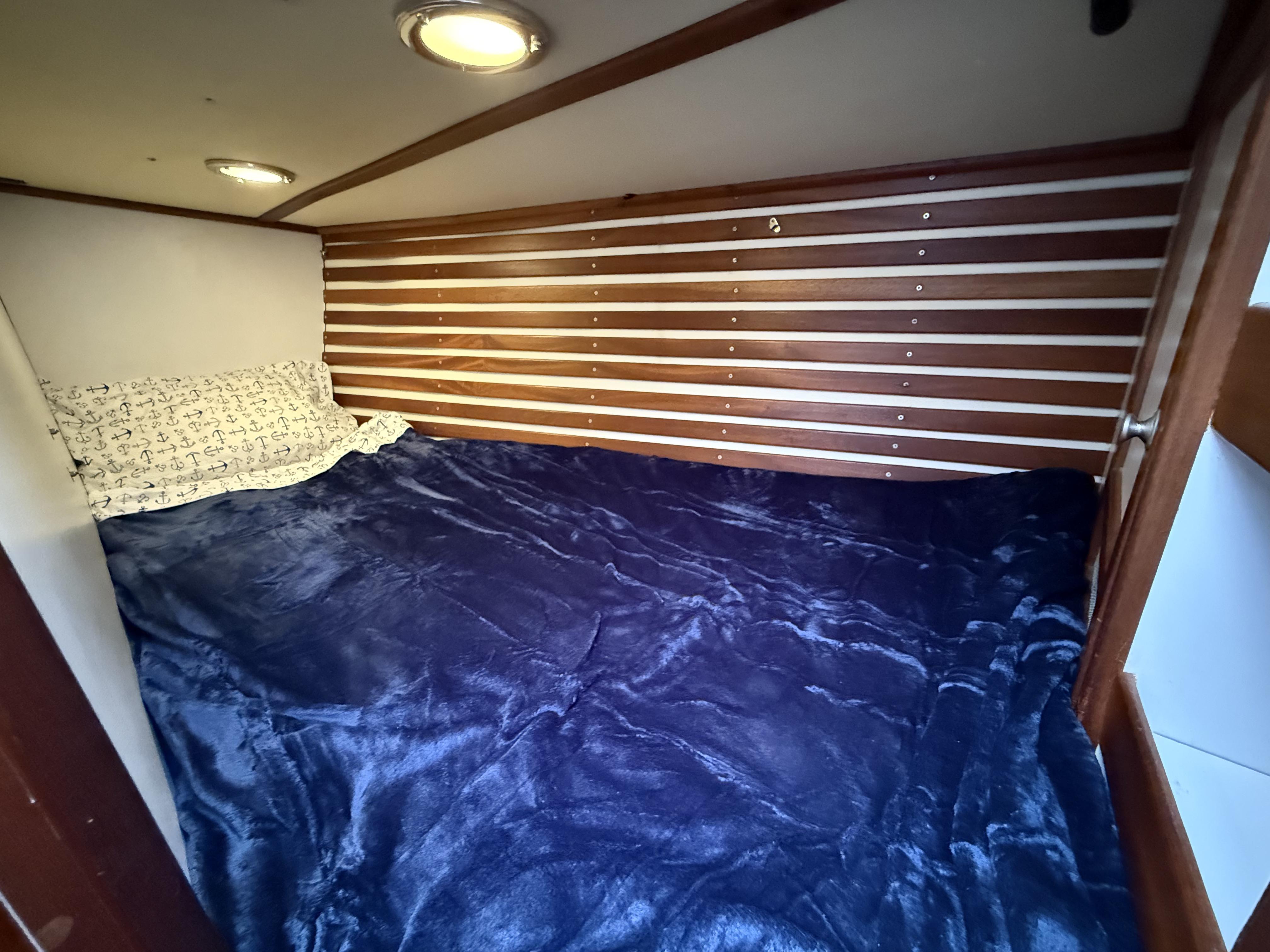 Cozy cabin bed in 1976 Frers Custom yacht with nautical-themed bedding.