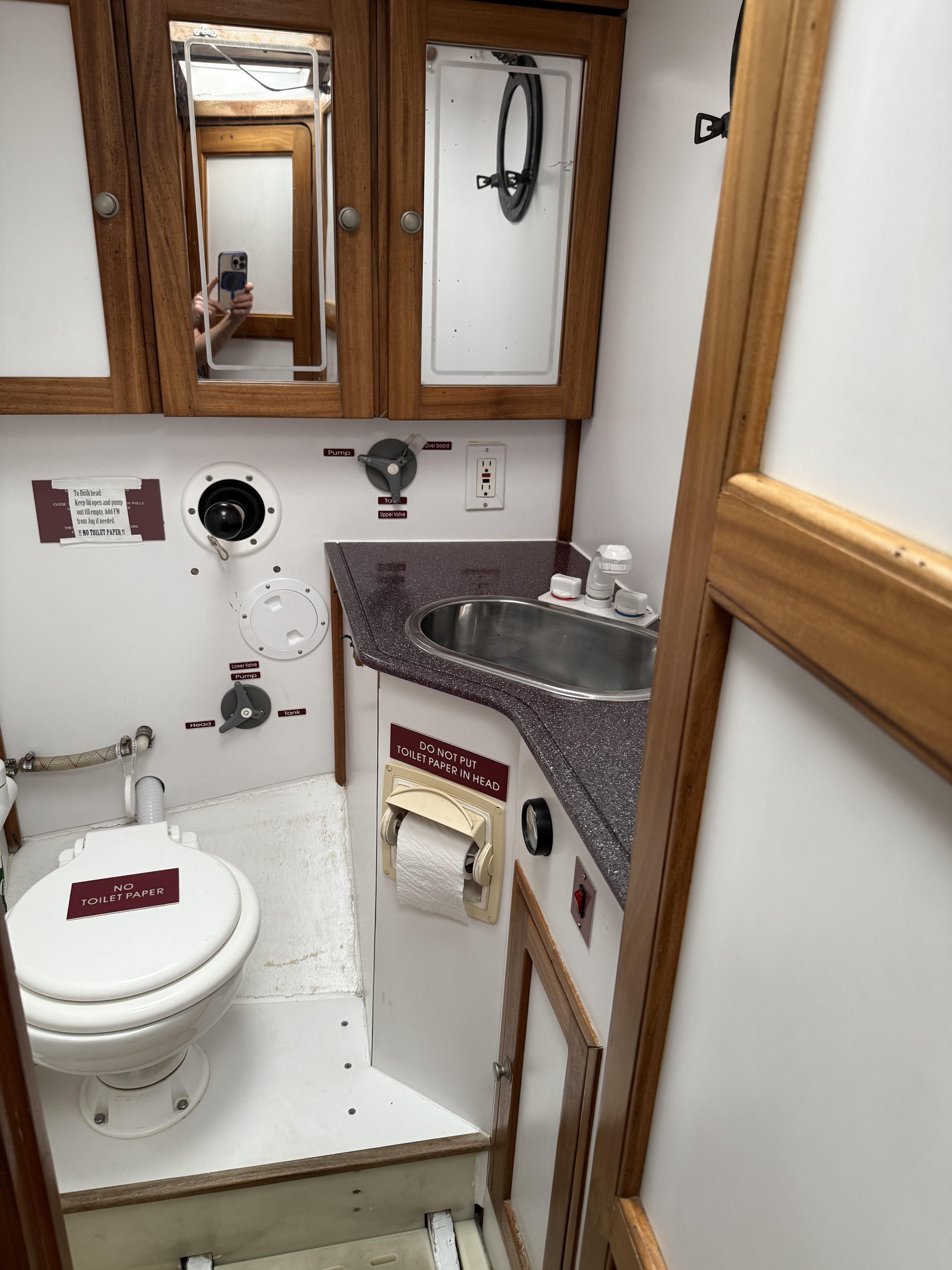 1976 Frers Custom yacht bathroom with wooden cabinets, sink, and marine toilet.