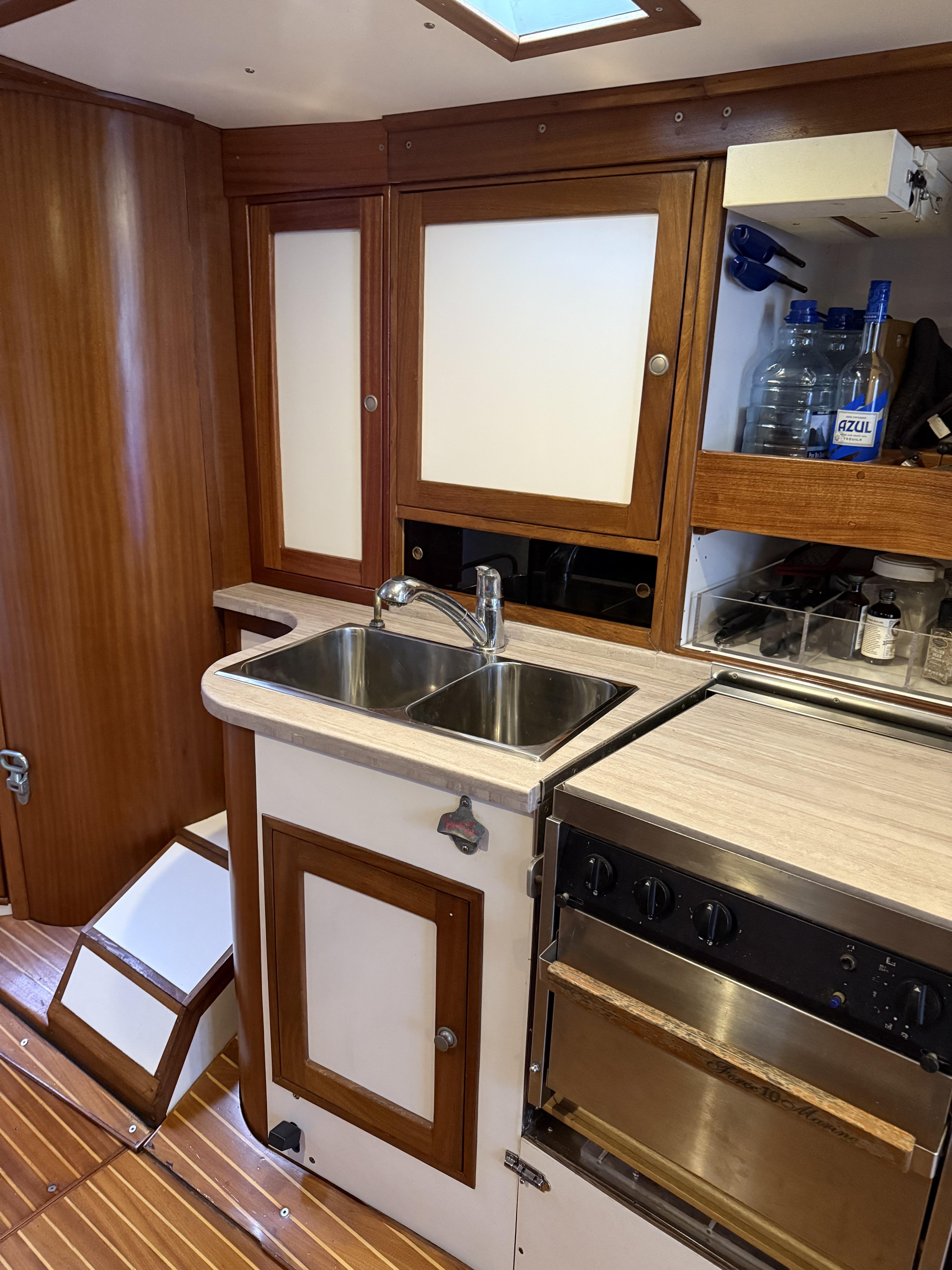 1976 Frers Custom yacht kitchen with wooden cabinets, sink, and stove.