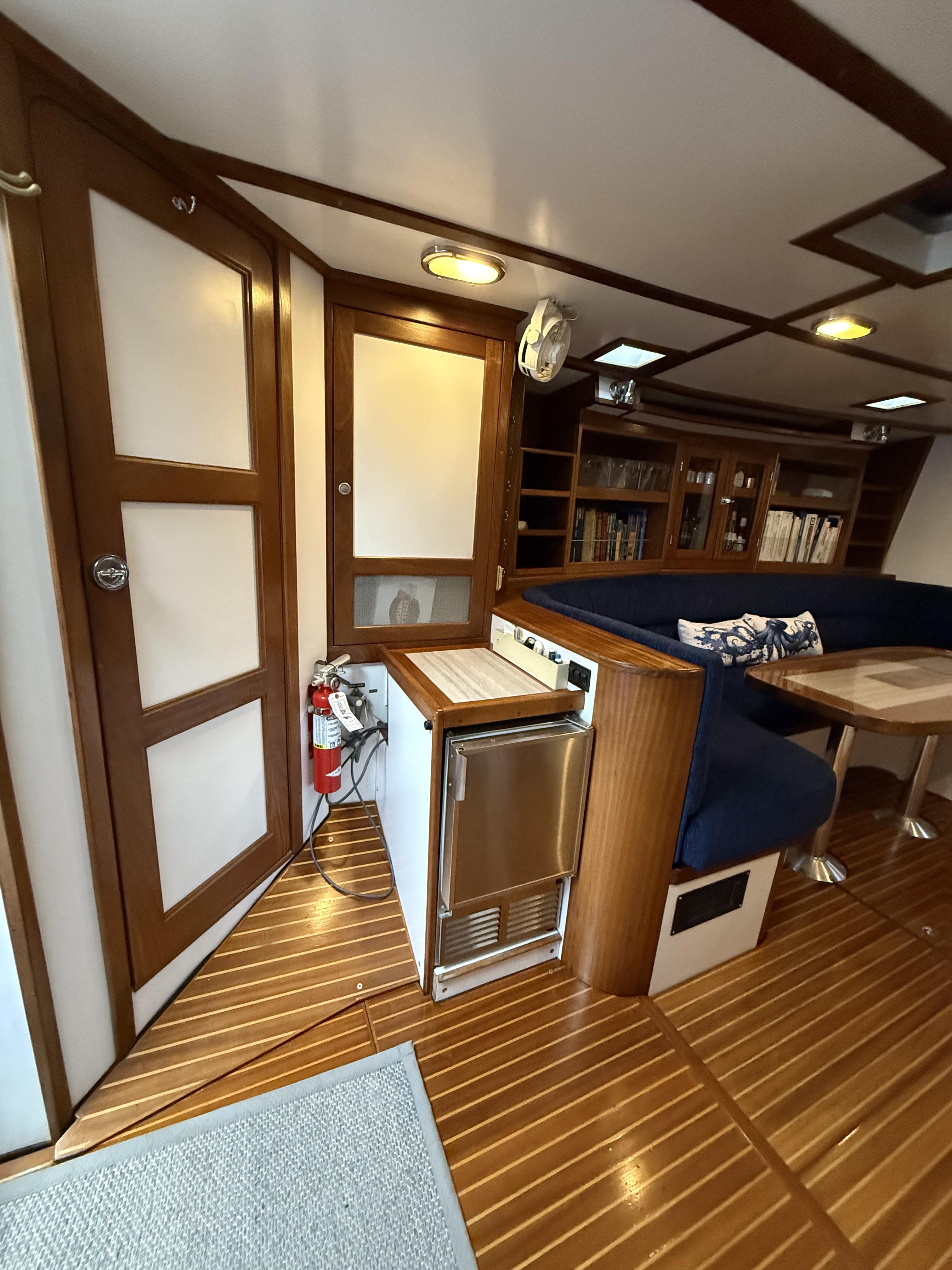 Interior of 1976 Frers Custom yacht with wood paneling, seating, and compact kitchen area.