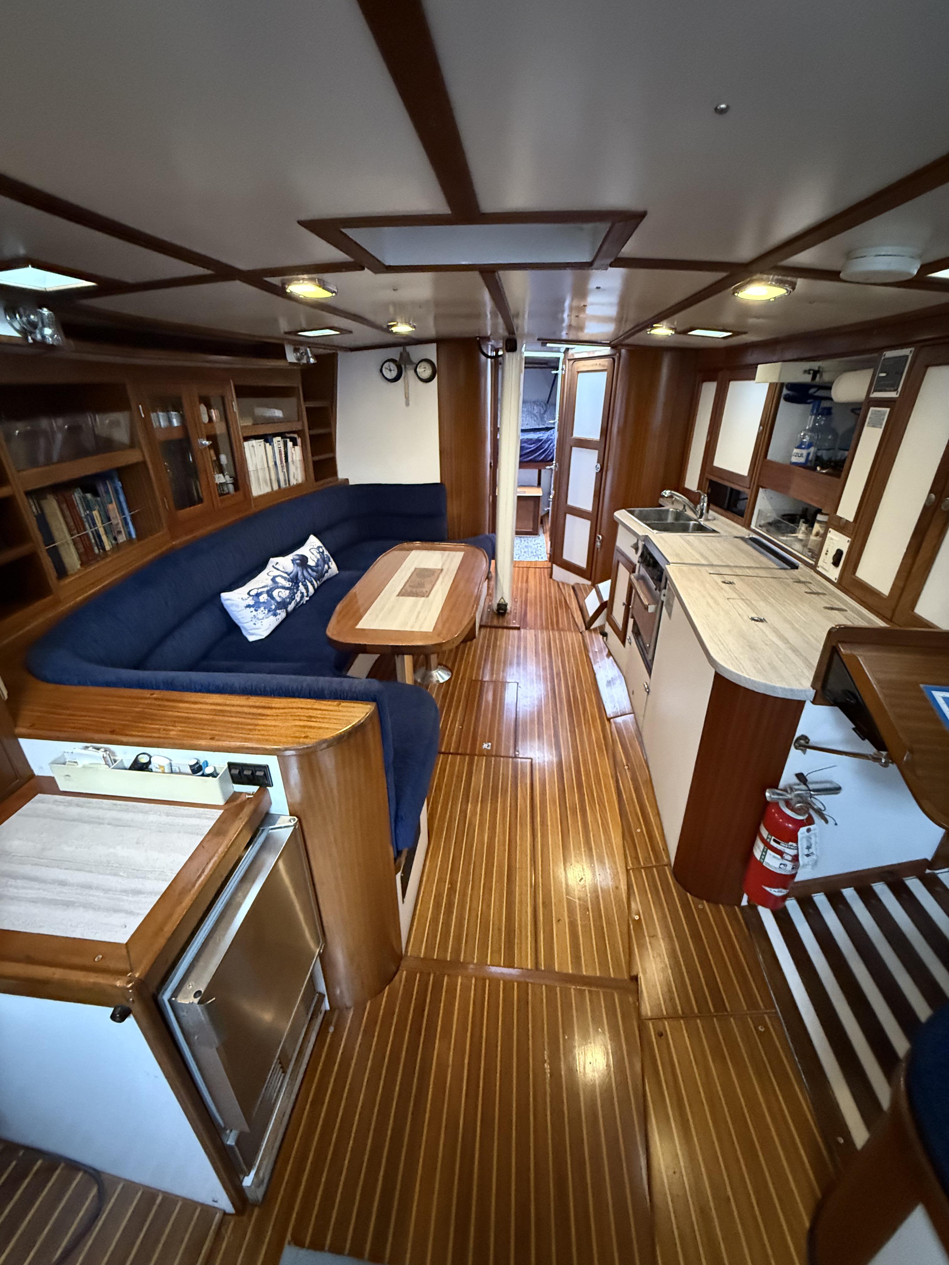 Interior of 1976 Frers Custom yacht with wooden flooring and cozy seating area.