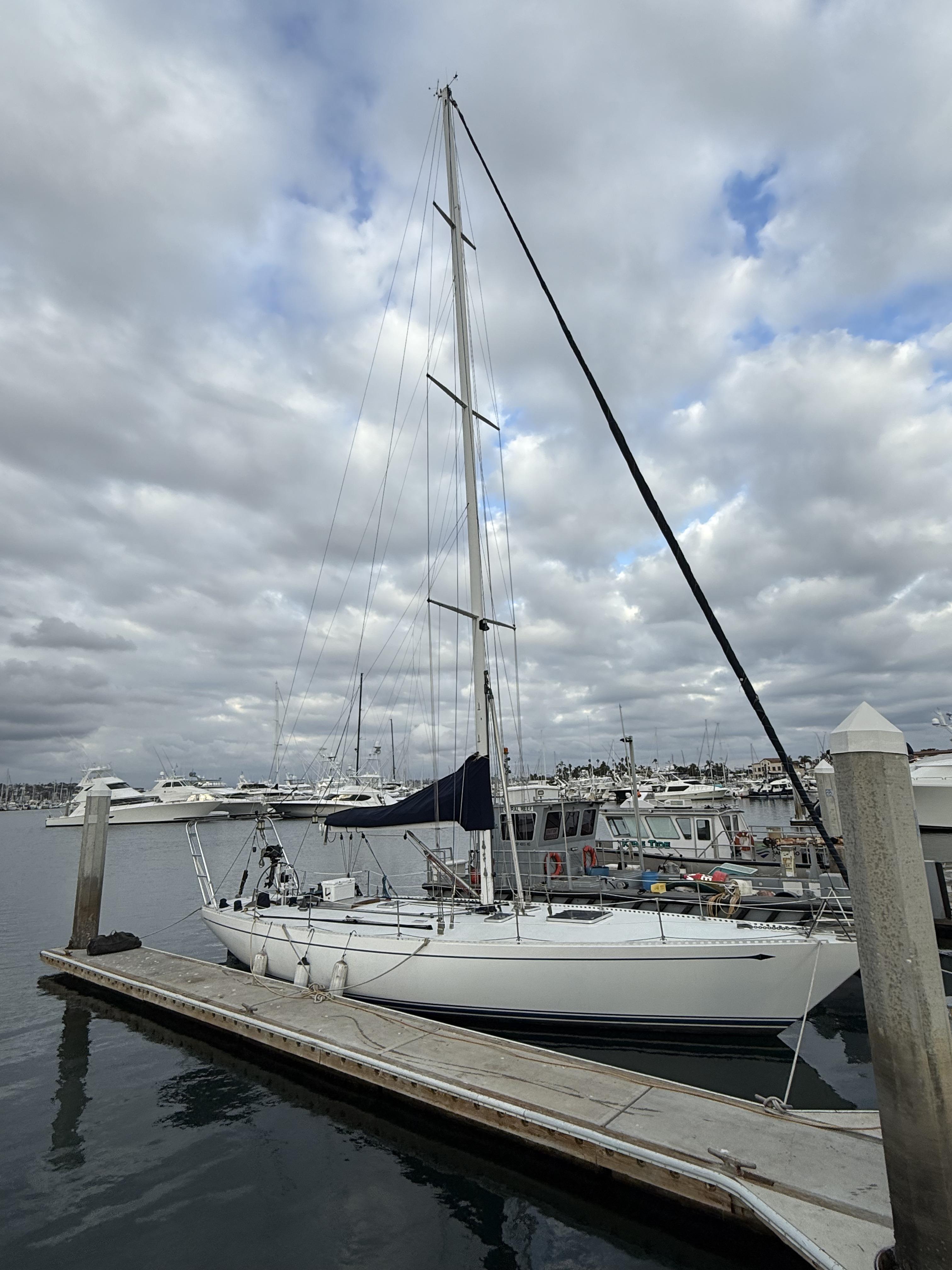 1976 Frers Custom sailboat docked at marina under cloudy sky.