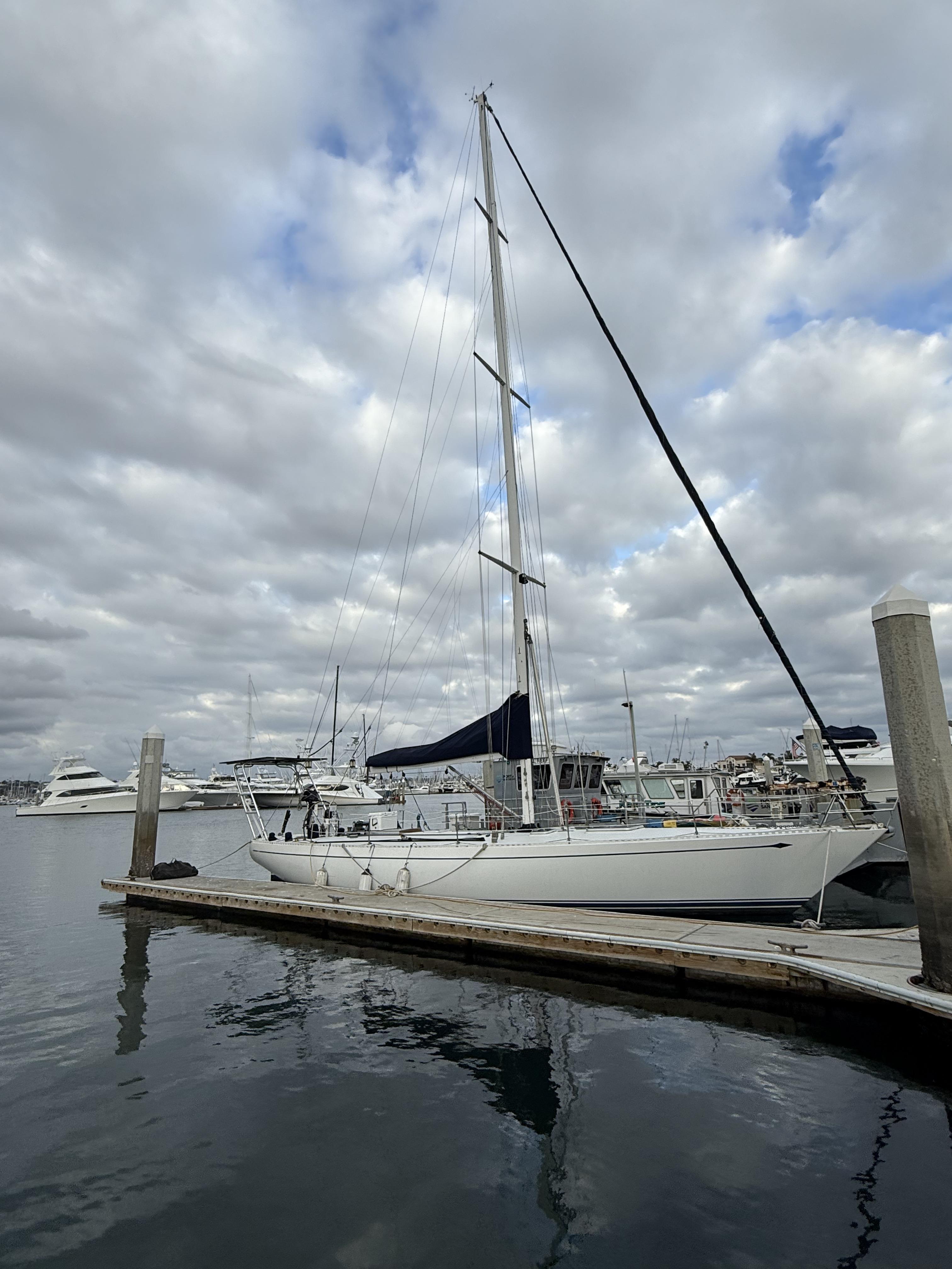 1976 Frers Custom sailboat docked at marina under cloudy sky.