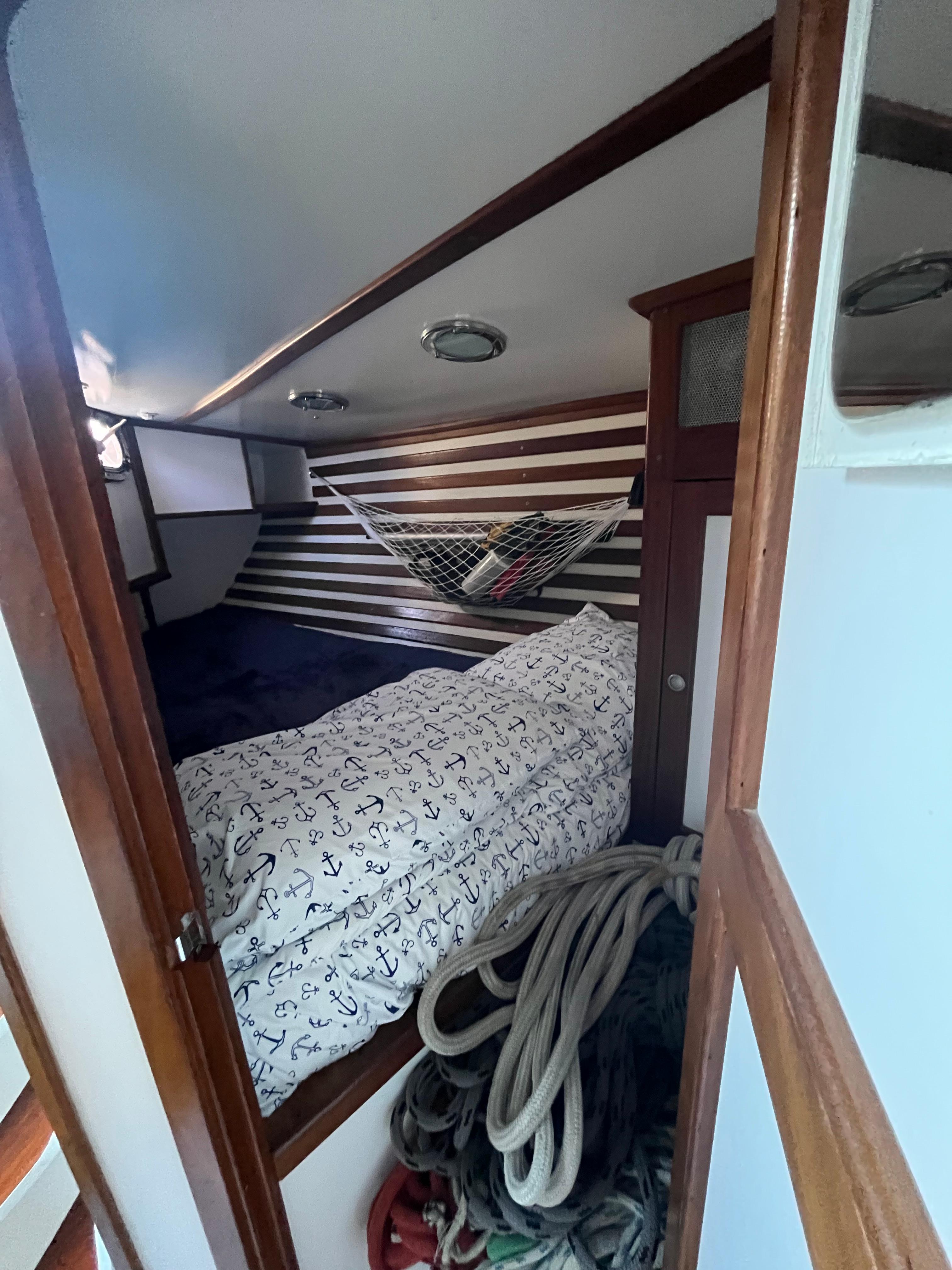 Cozy cabin interior of 1976 Frers Custom boat with nautical bedding and ropes.
