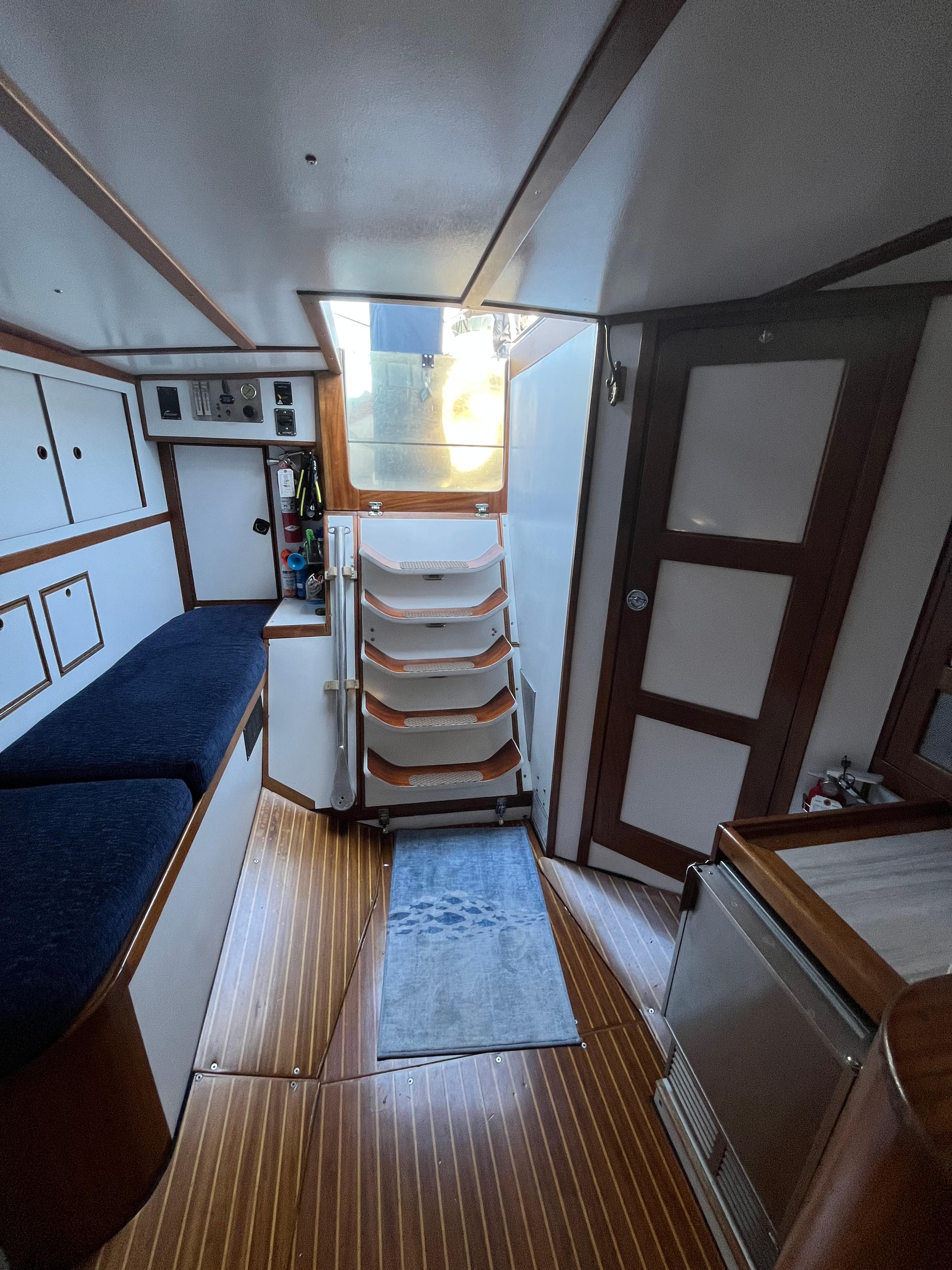 Interior of 1976 Frers Custom yacht with wooden flooring and white cabinetry.
