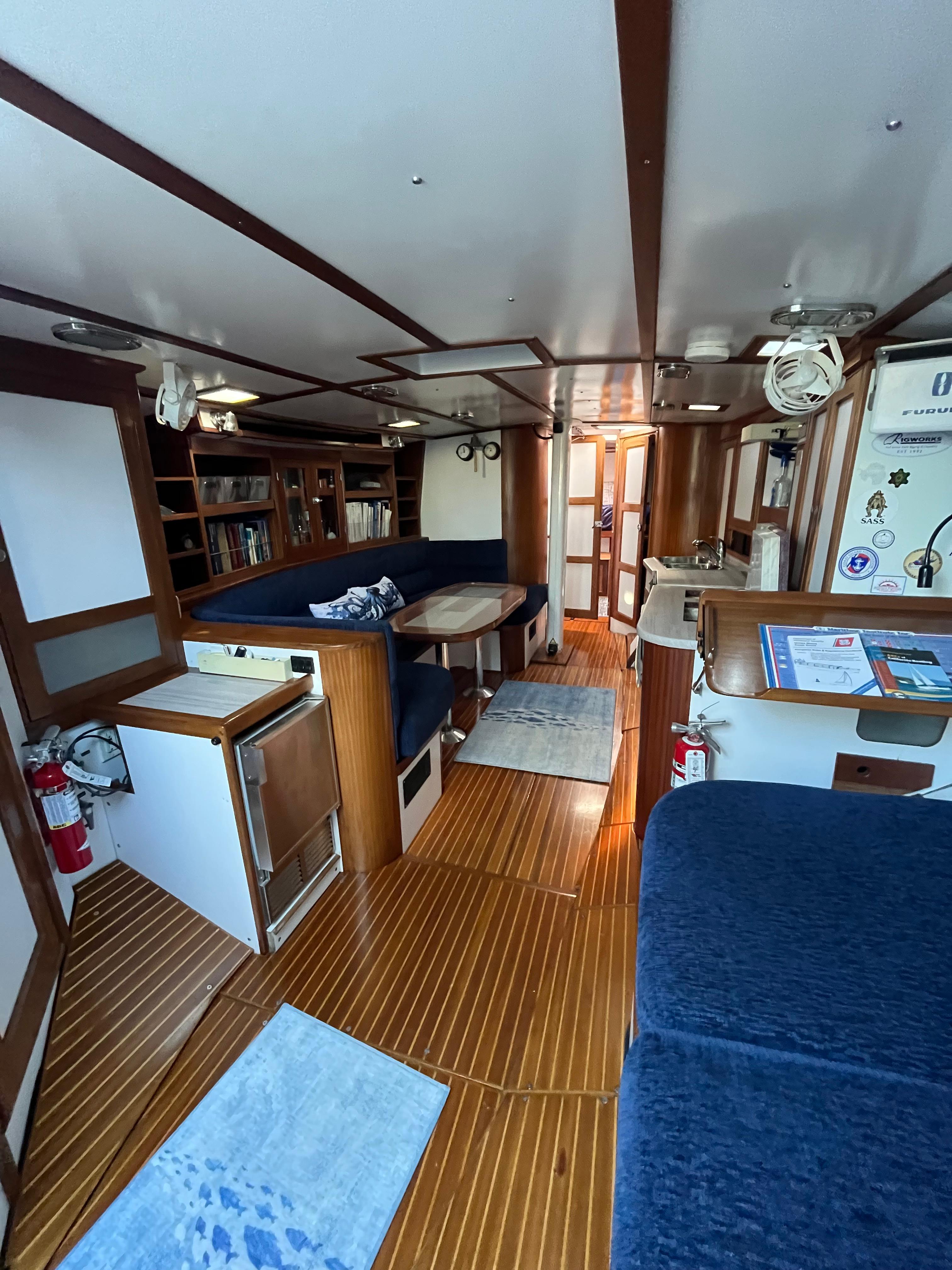 Interior of a 1976 Frers Custom yacht with wooden flooring and blue seating.