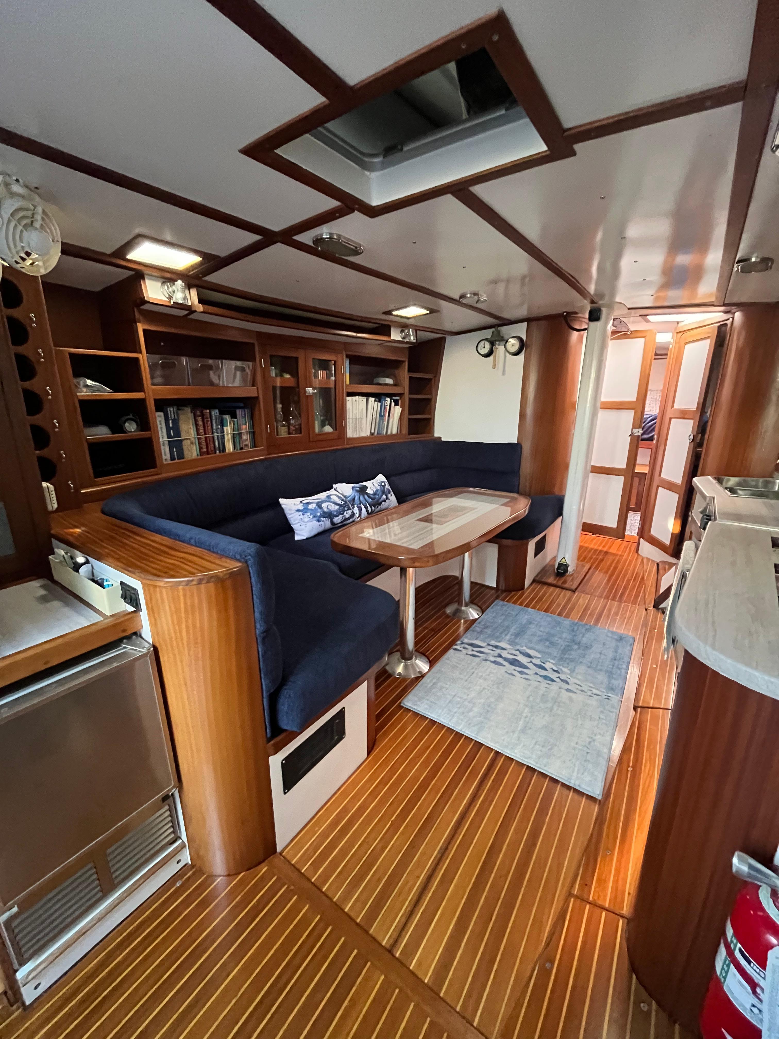 Interior of 1976 Frers Custom yacht with wooden flooring and blue seating.