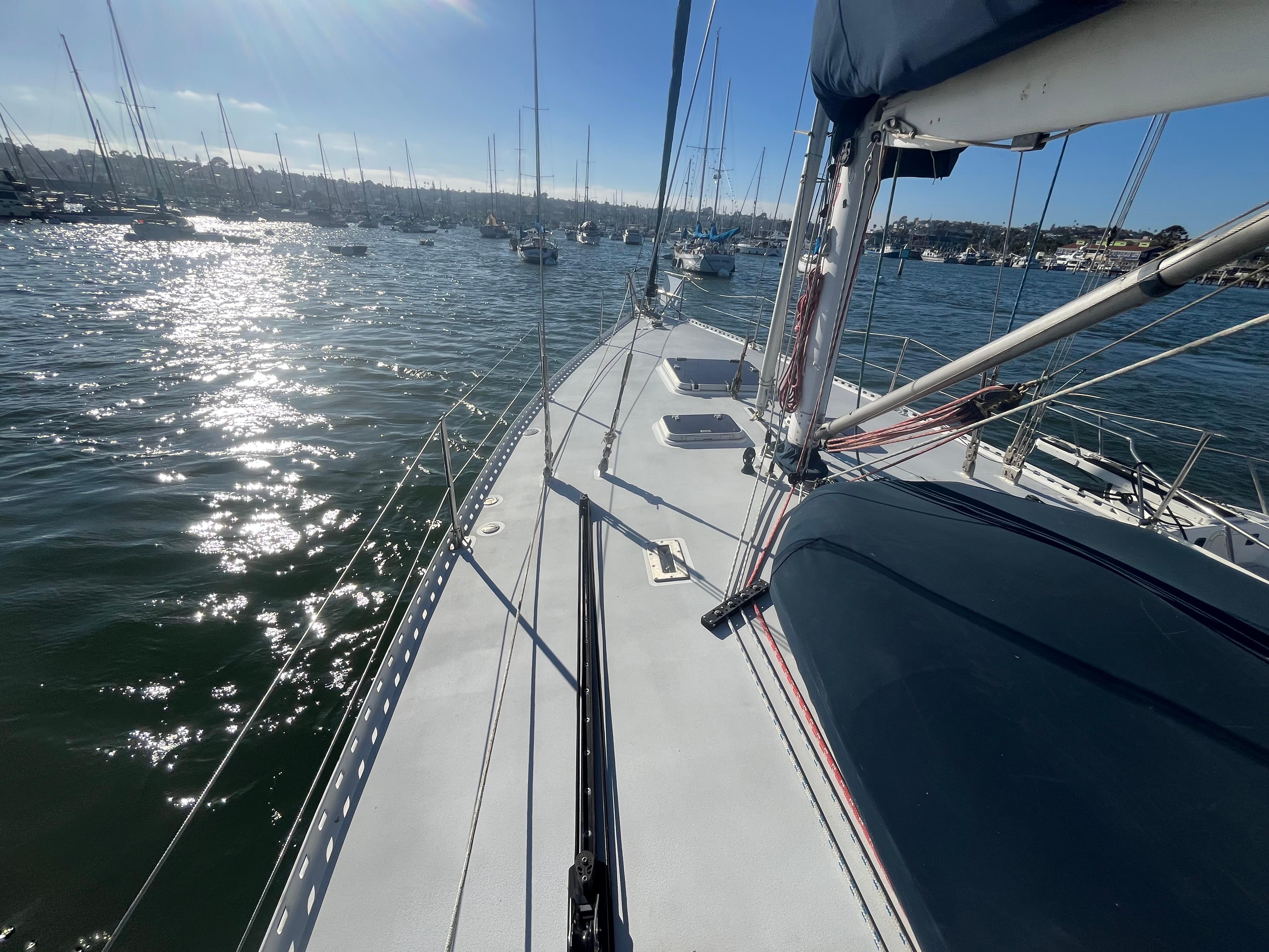 Sailboat deck view on water, Frers Custom 1976, sunny day, marina background.
