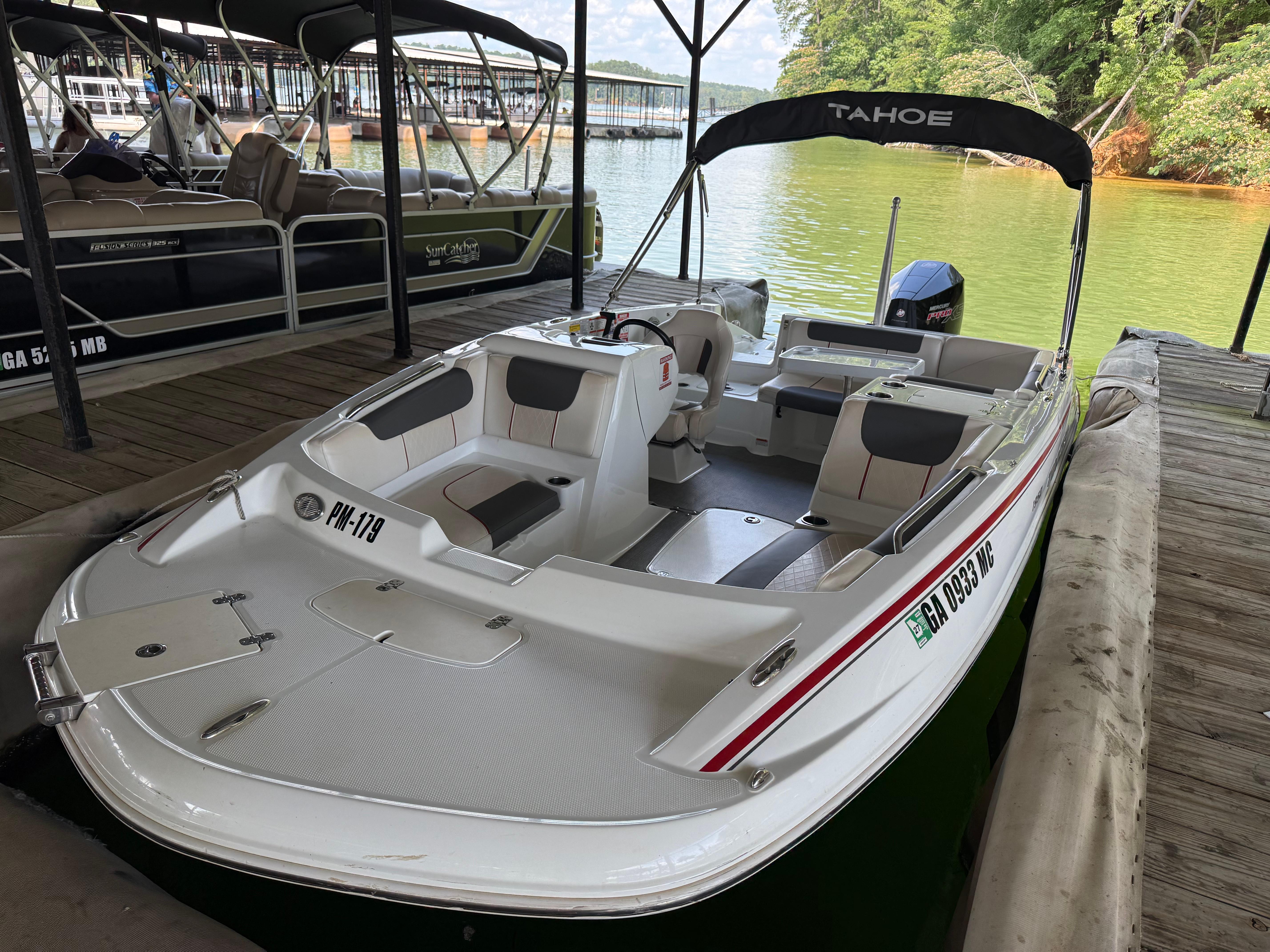 Tahoe 1950 boat docked on a lake, 2021 model, with canopy and seating.