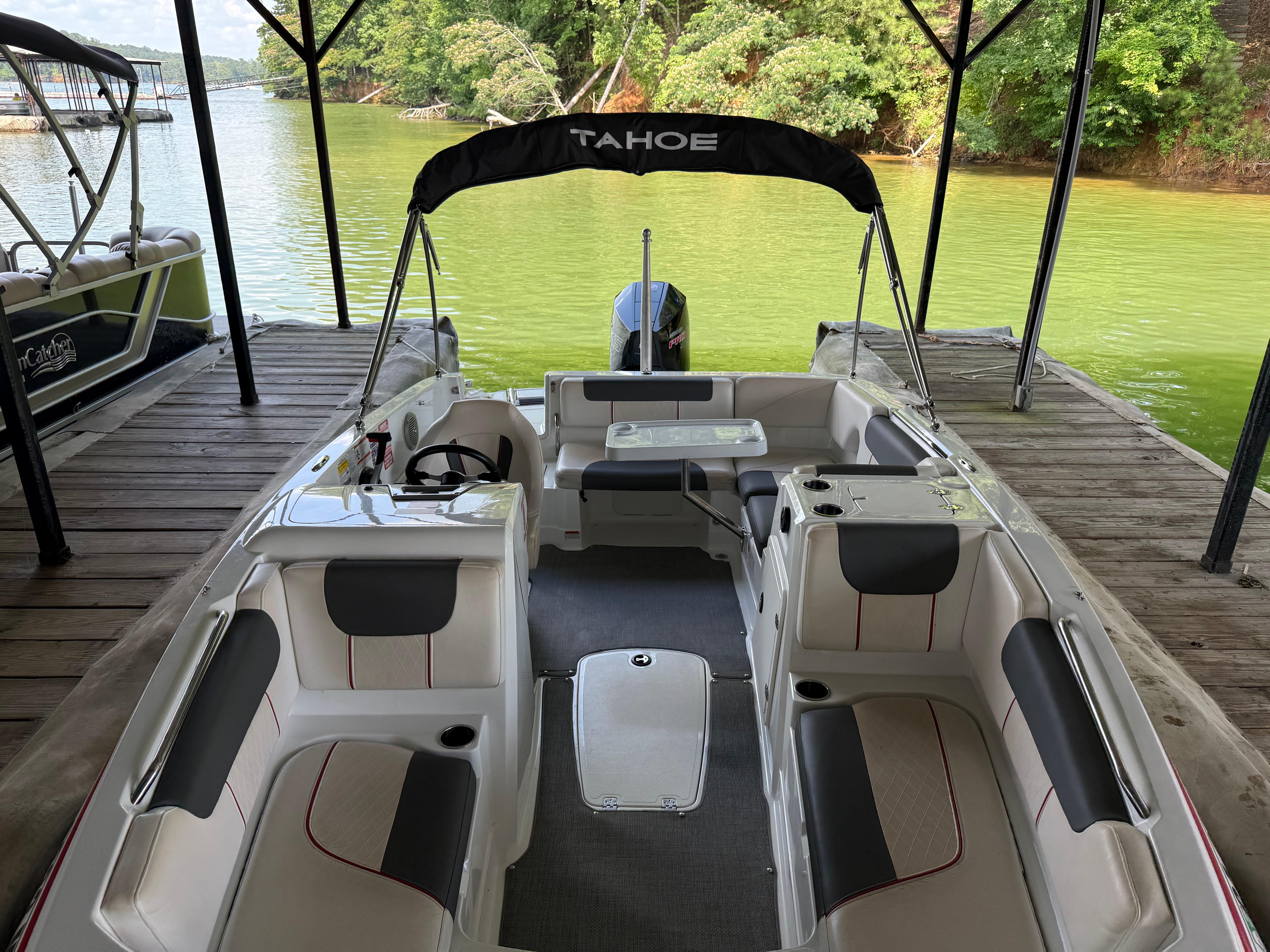 2021 Tahoe 1950 boat docked on a serene lake with lush greenery.
