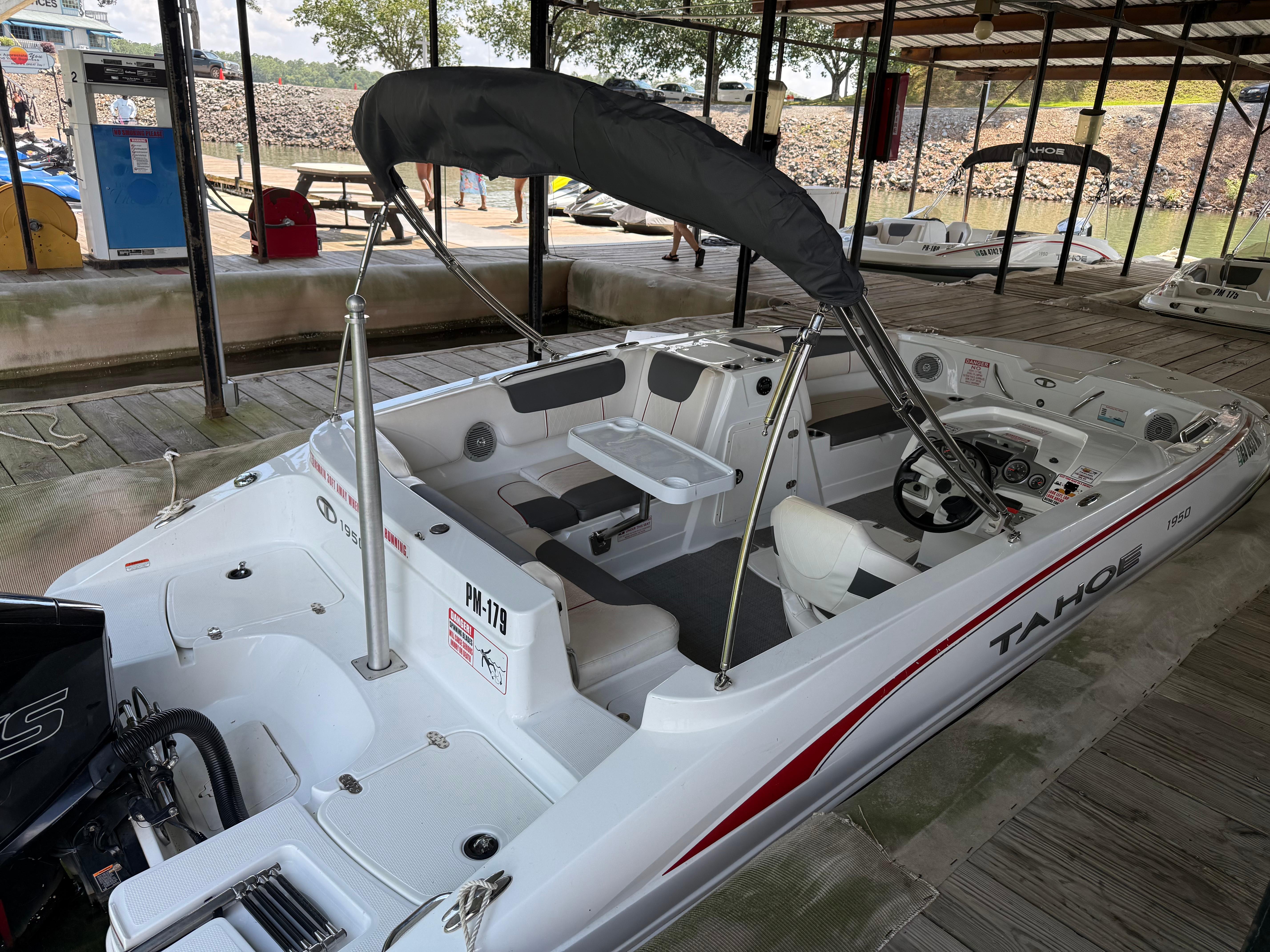 2021 Tahoe 1950 boat docked, featuring a sleek design and spacious interior under a canopy.