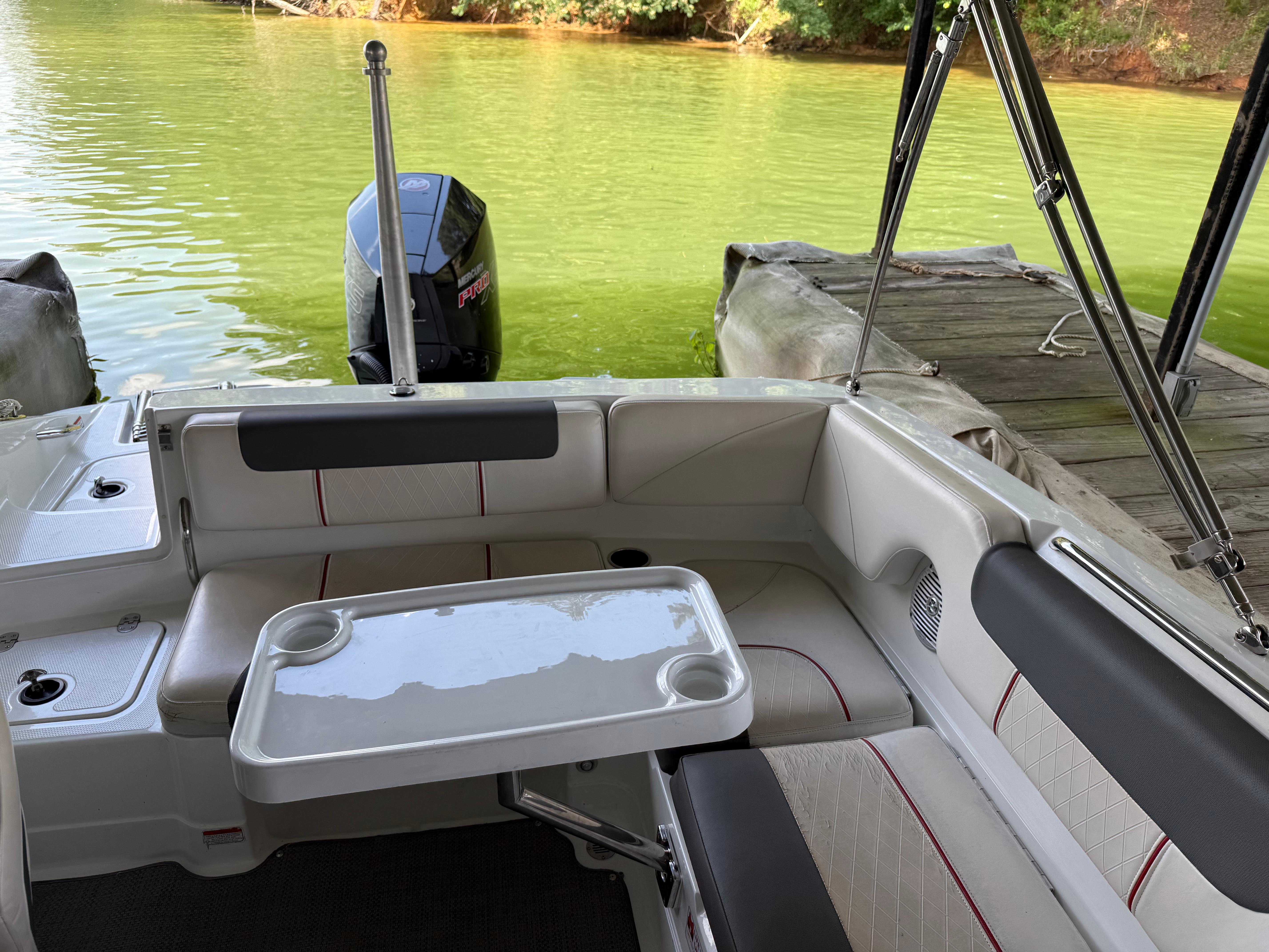 Boat interior with seating and table, docked on a lake. Tahoe 1950, 2021 model.