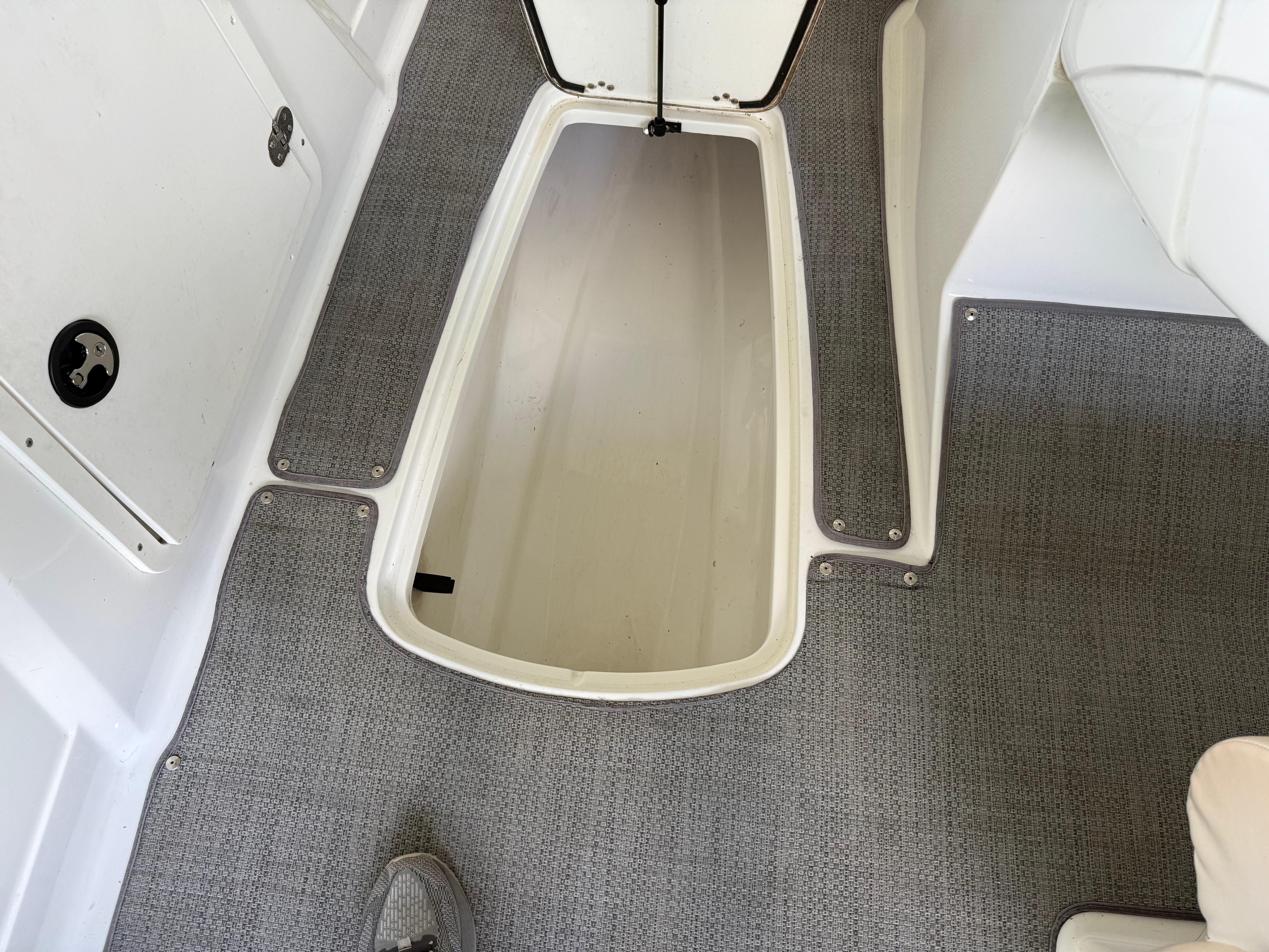 Open storage compartment on a 2021 Tahoe 1950 boat with gray carpet flooring.