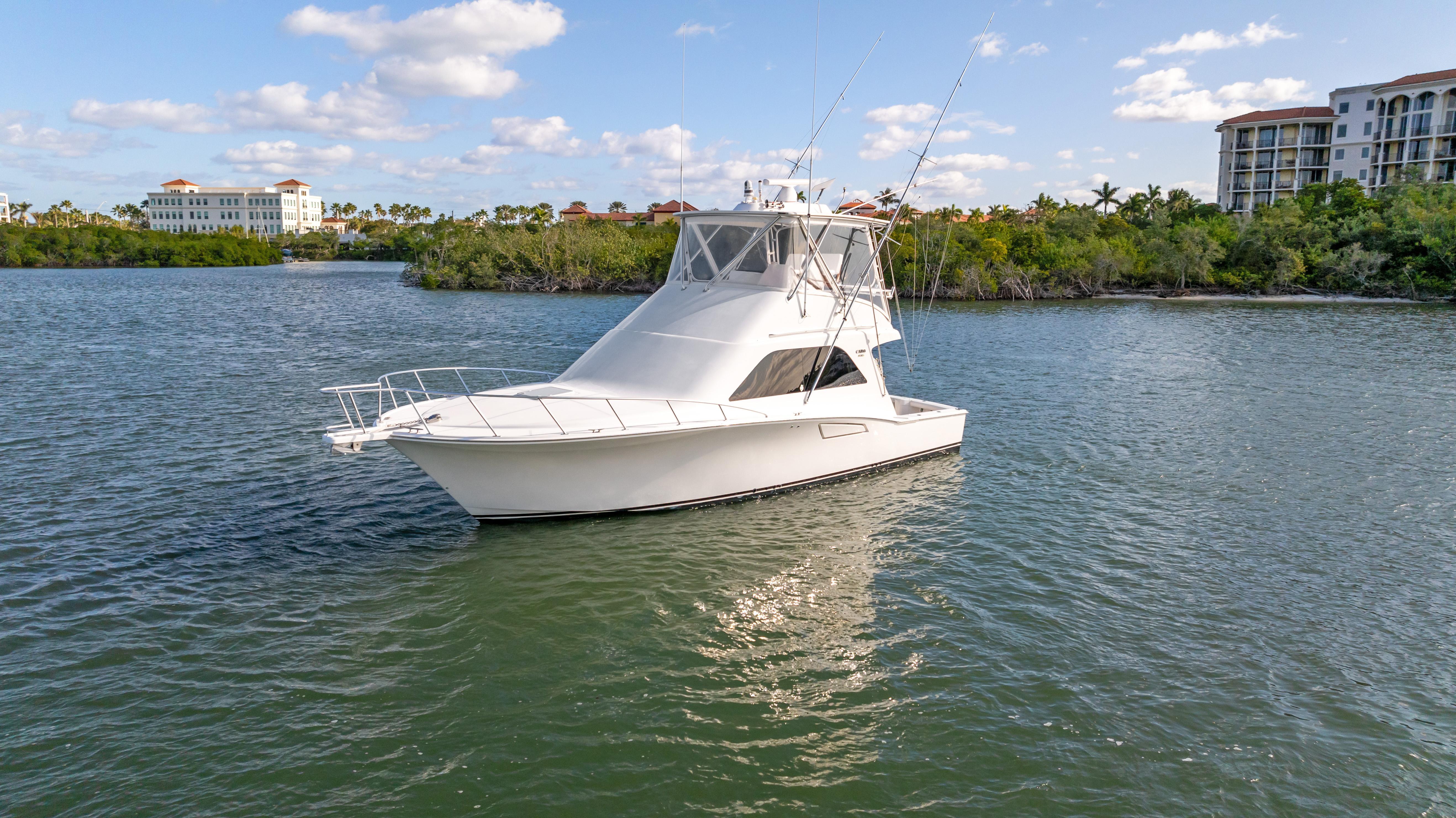 Cabo-40 Flybridge 2011-WELL PLAYED FL-US-2011 Cabo 40 Flybridge yacht on calm water, surrounded by lush greenery and buildings.-9659613