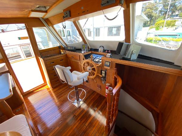 Interior of 1977 Grand Alaskan Raised Pilothouse with wooden helm and modern navigation equipment.