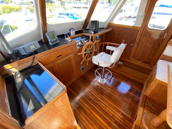 Grand Alaskan Raised Pilothouse 1977 interior with wooden helm and navigation equipment.