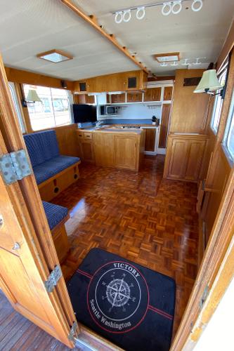 Interior of 1977 Grand Alaskan Raised Pilothouse with wood flooring and cozy seating area.