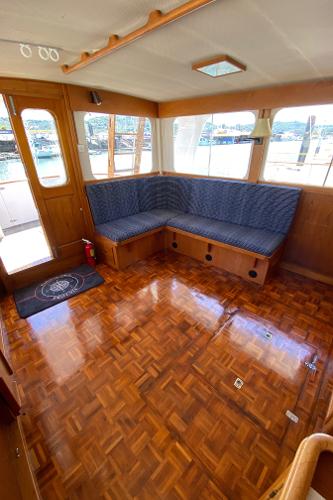 1977 Grand Alaskan Raised Pilothouse interior with wood flooring and blue cushioned seating.