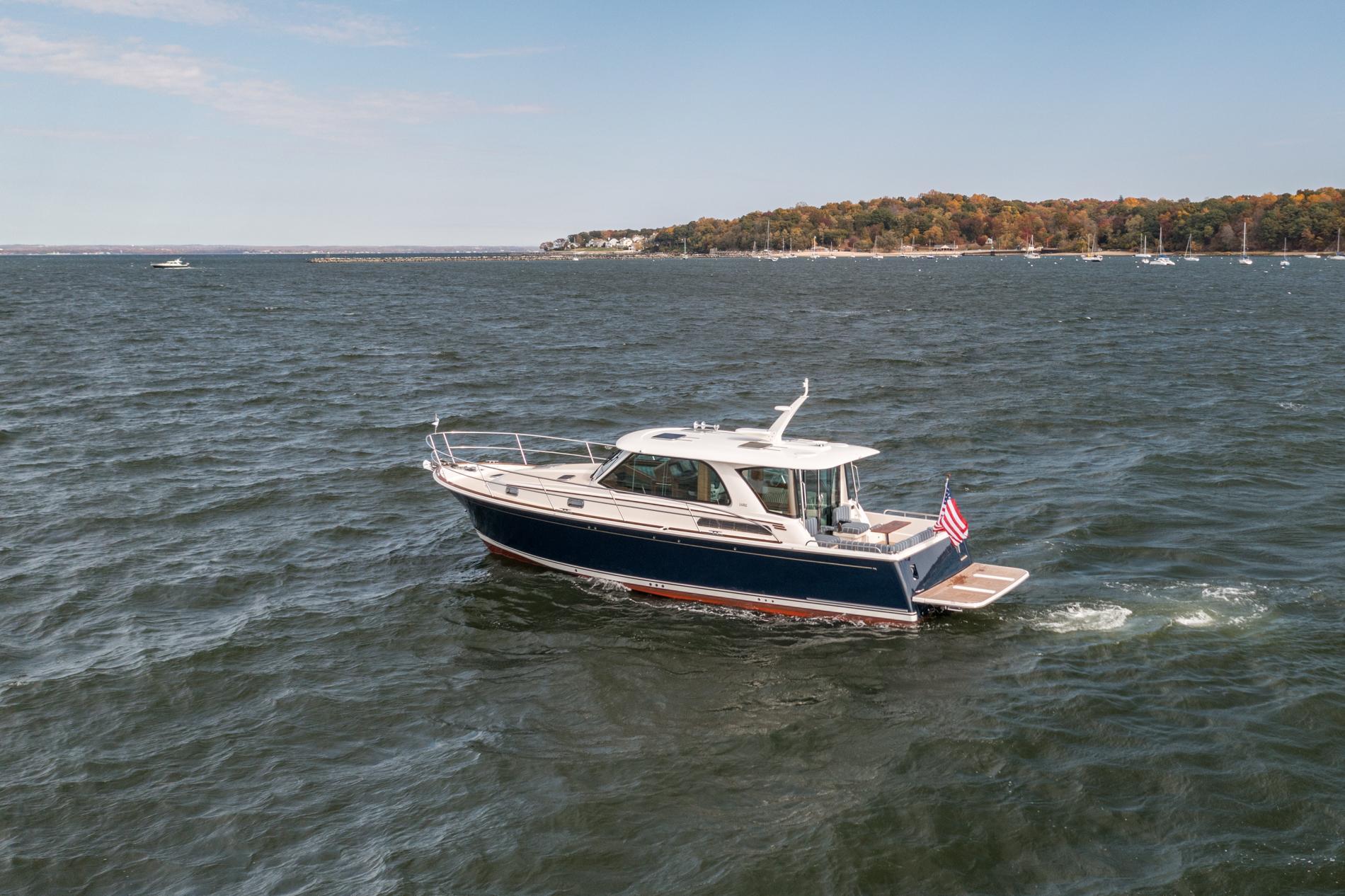 2025 Sabre 43 Salon Express yacht cruising on a scenic lake with distant shoreline.