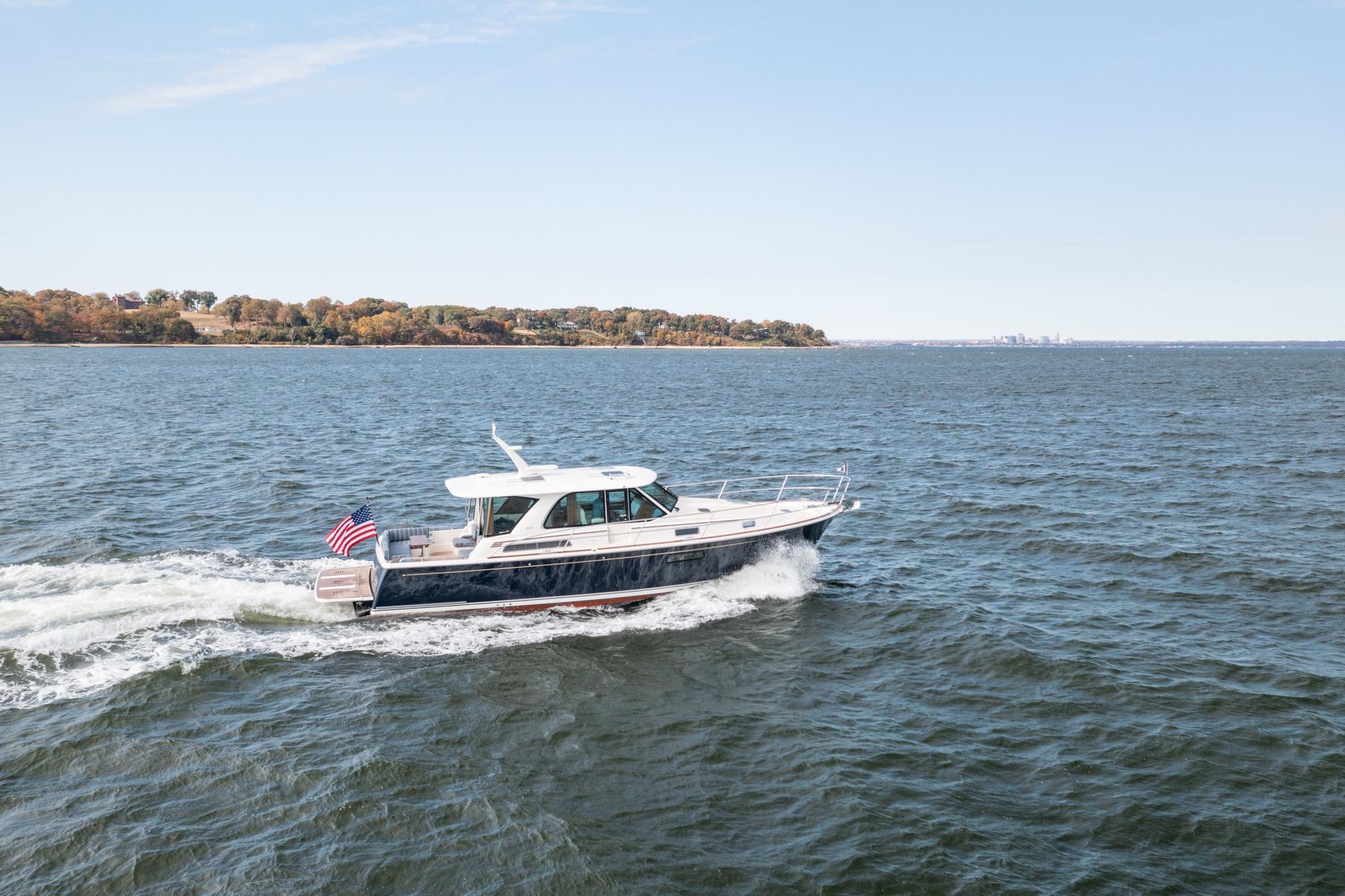 2025 Sabre 43 Salon Express yacht cruising on open water, American flag displayed.