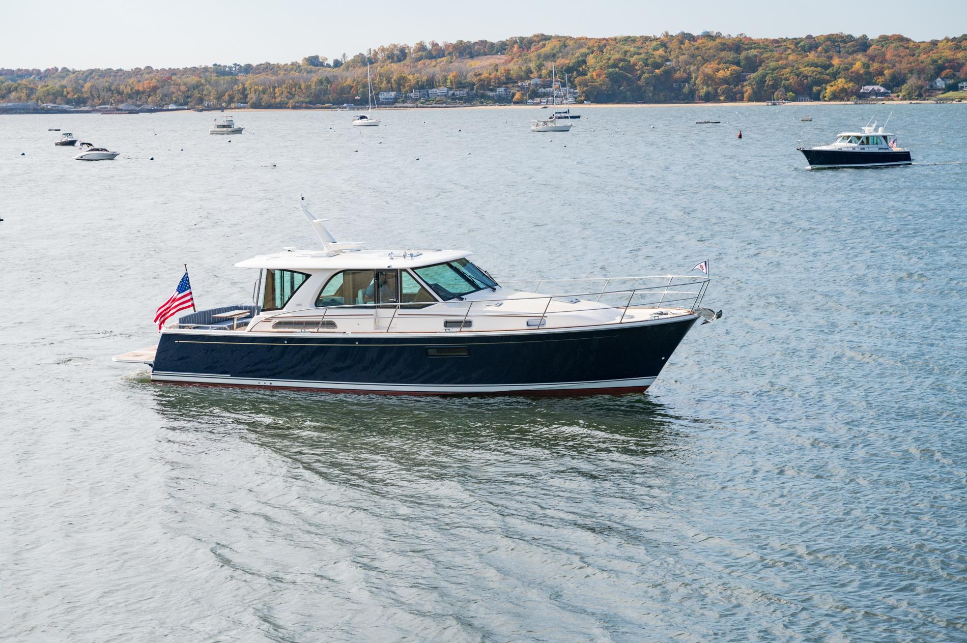 2025 Sabre 43 Salon Express yacht cruising on a scenic lake with autumn foliage.