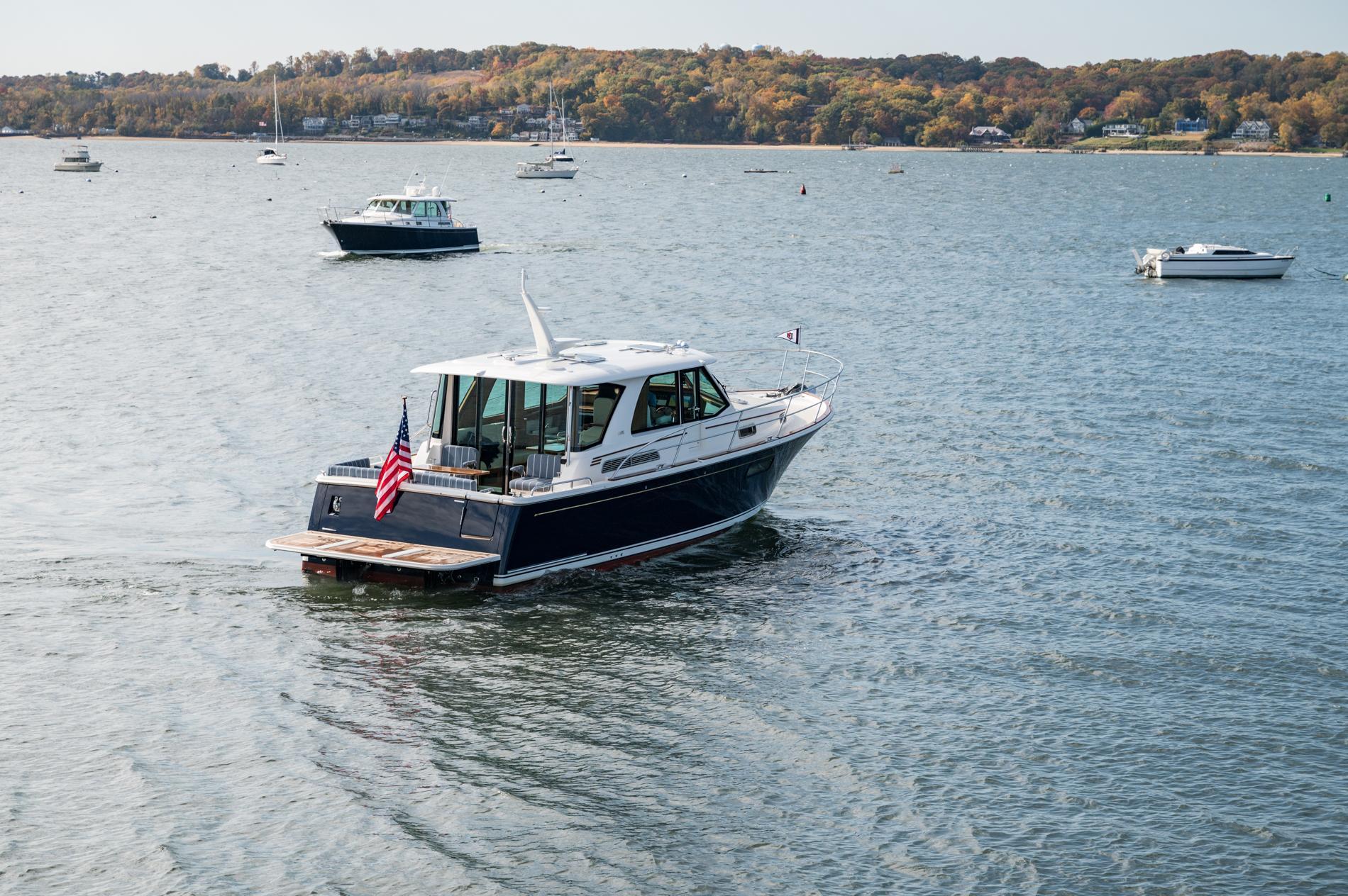 2025 Sabre 43 Salon Express cruising on a scenic lake with other boats.