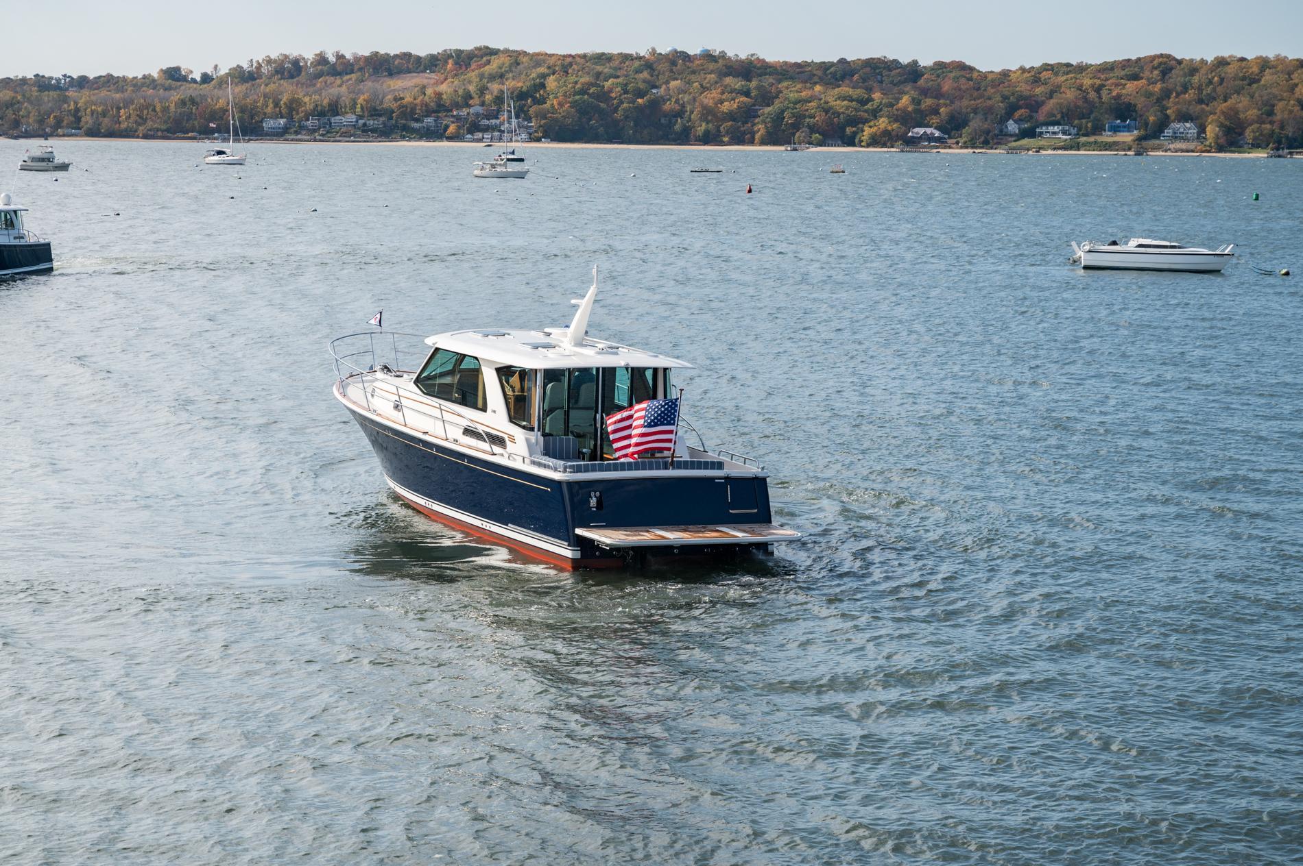 2025 Sabre 43 Salon Express yacht cruising on a scenic lake with autumn foliage.