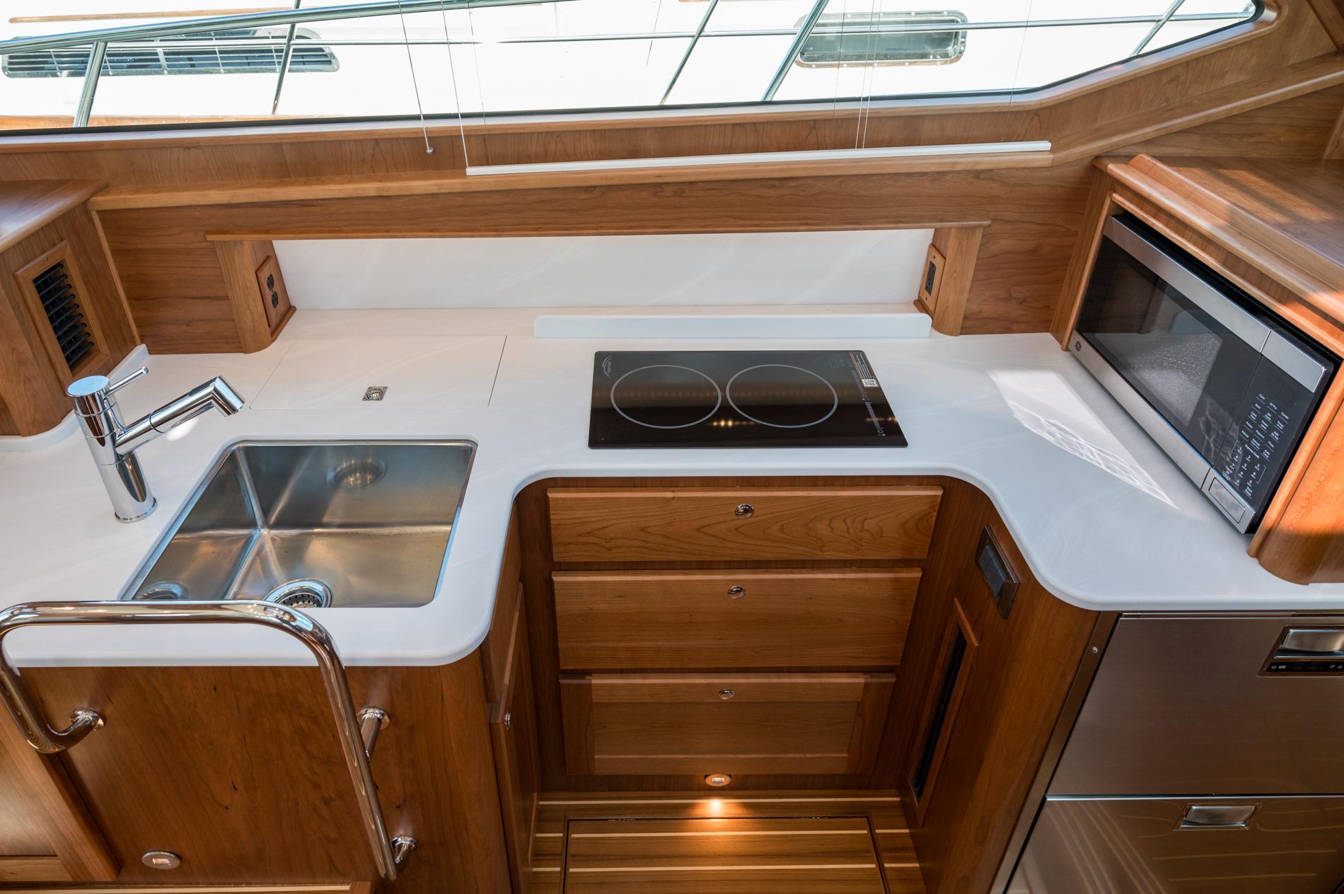 Modern kitchen in 2025 Sabre 43 Salon Express yacht with stove, sink, and microwave.