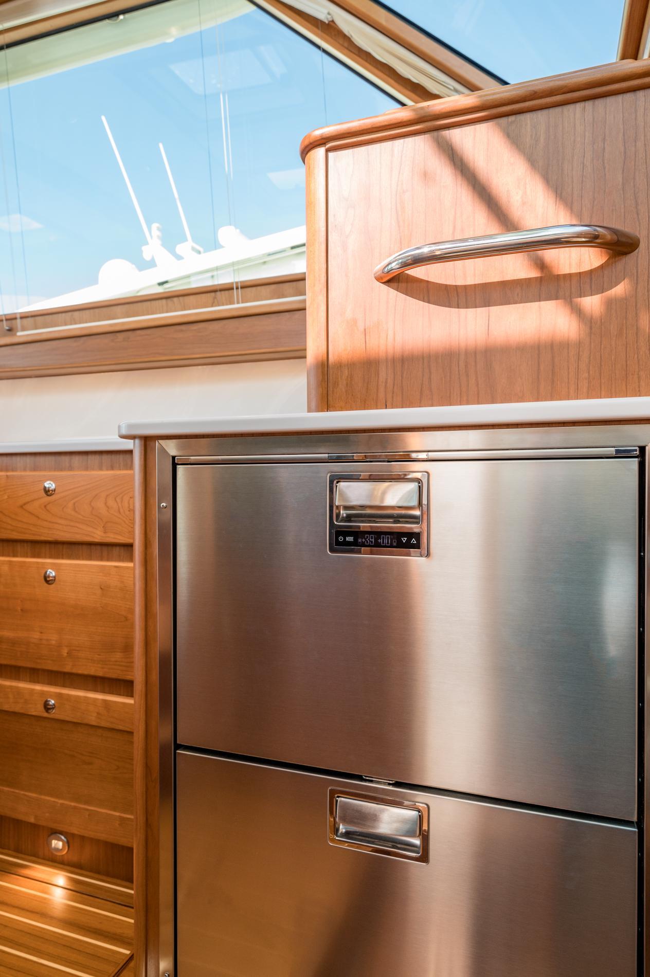 Modern kitchen interior of 2025 Sabre 43 Salon Express yacht, featuring stainless steel appliances and wood cabinetry.