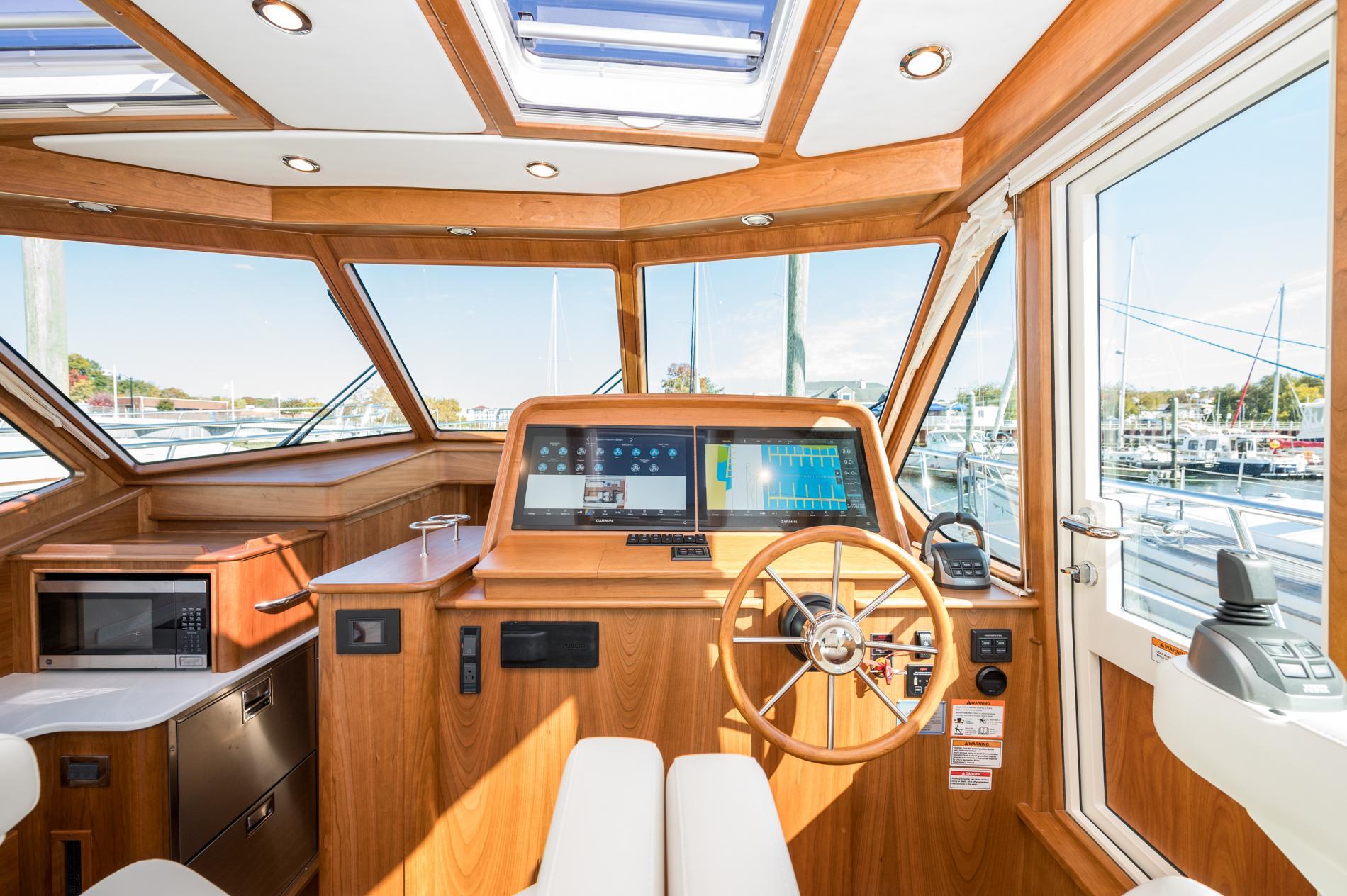 2025 Sabre 43 Salon Express helm with modern navigation, wooden interior, and marina view.