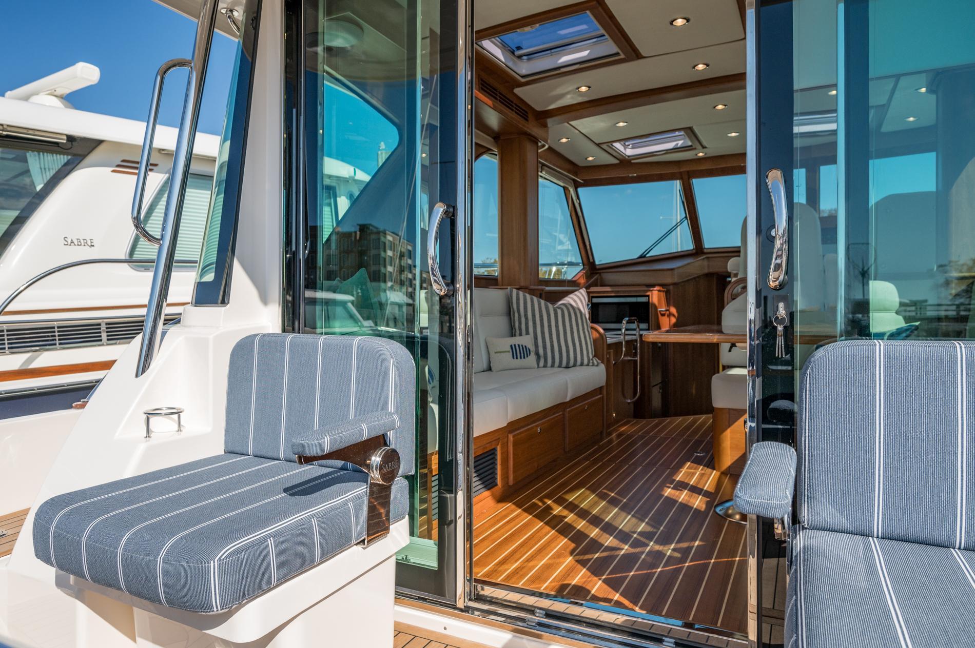 2025 Sabre 43 Salon Express yacht interior with striped seating and wooden flooring.