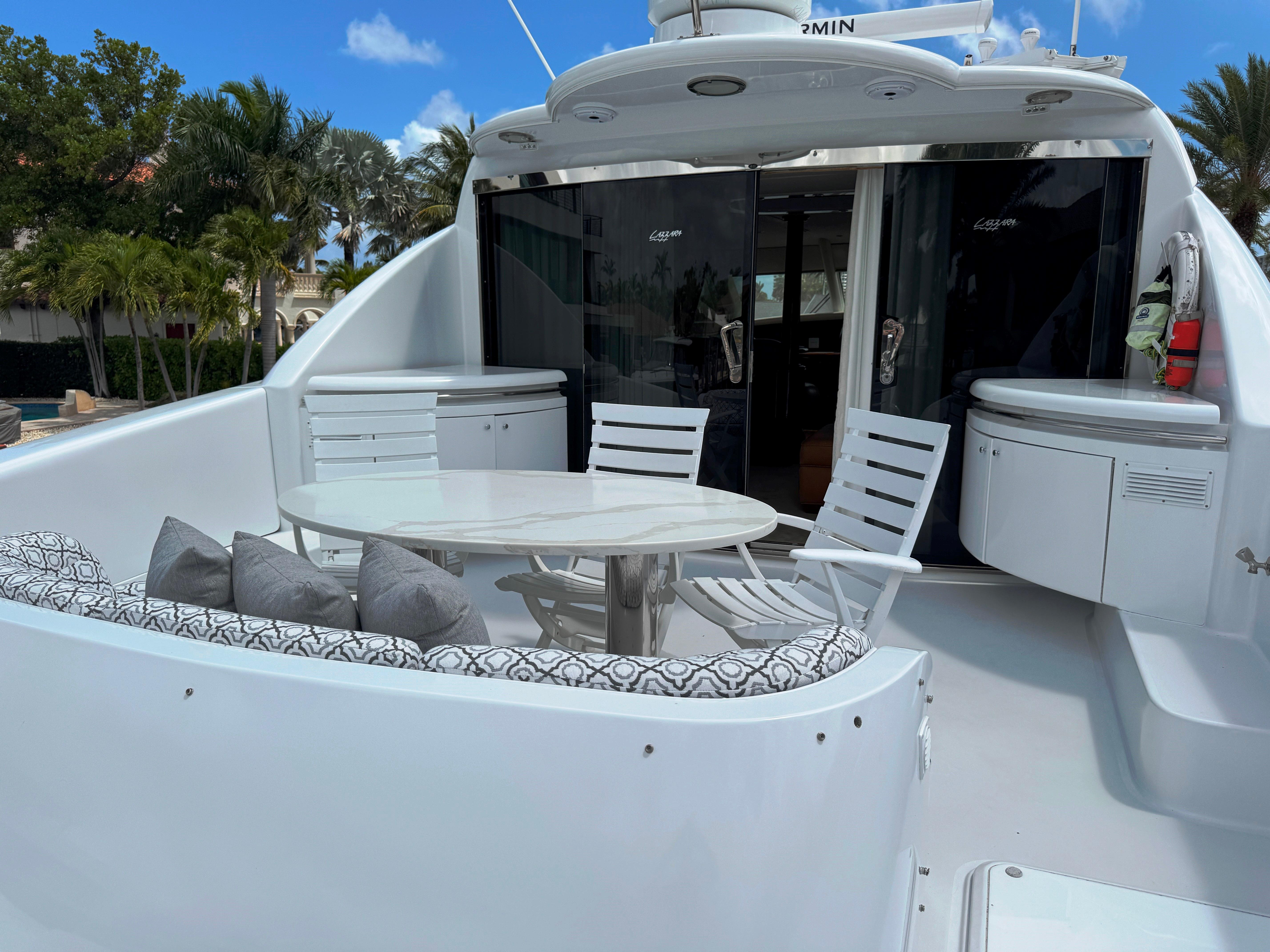 Lazzara-80 Skylounge 2002-Fomo2 FL-US-Luxury 2002 Lazzara 80 Skylounge yacht deck with seating and table, under clear blue sky.-9749638 | Thumbnail