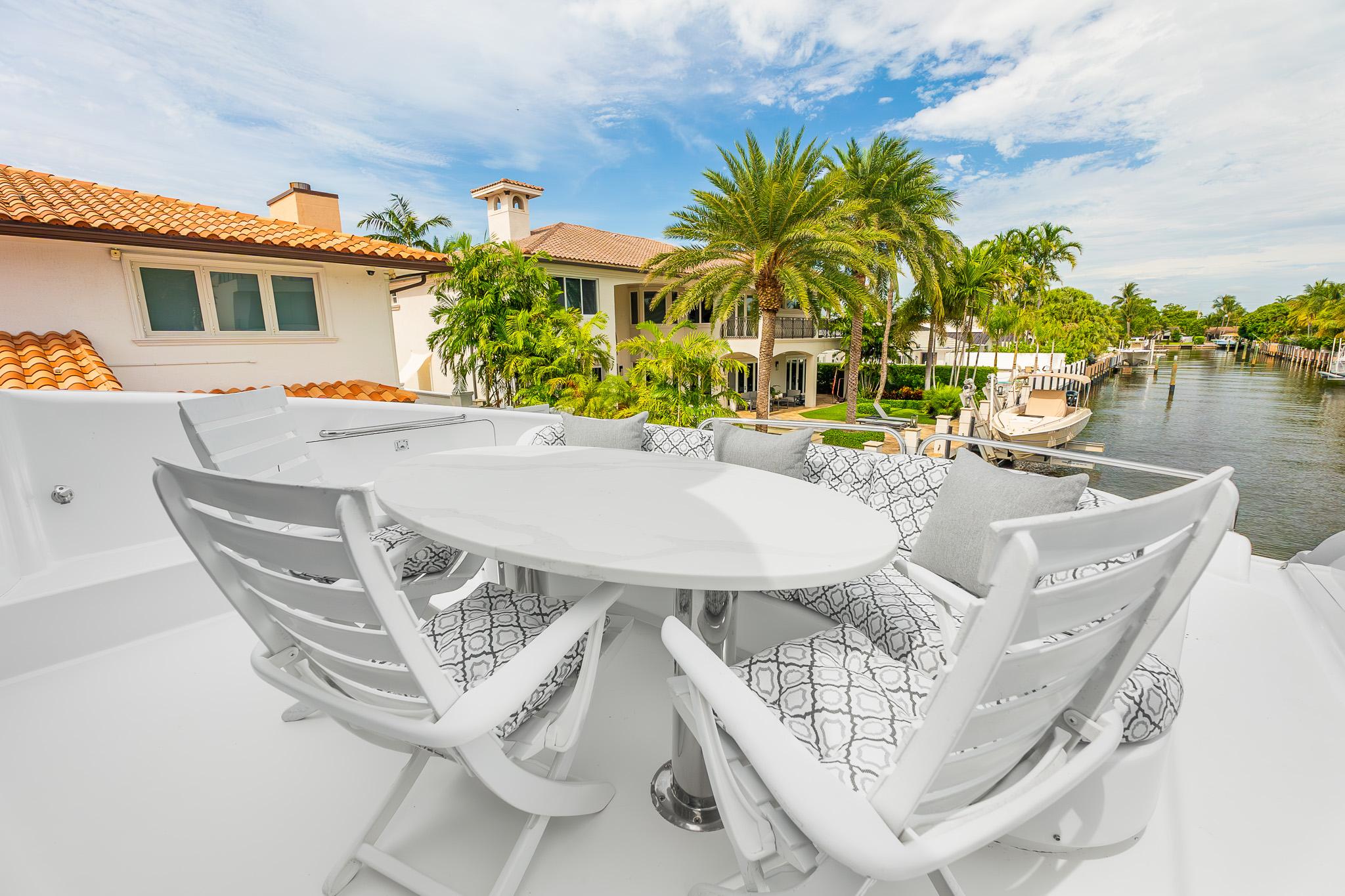 Lazzara-80 Skylounge 2002-Fomo2 FL-US-Luxury yacht deck with white seating, table, and waterfront view; Lazzara 80 Skylounge, 2002.-9749638 | Thumbnail