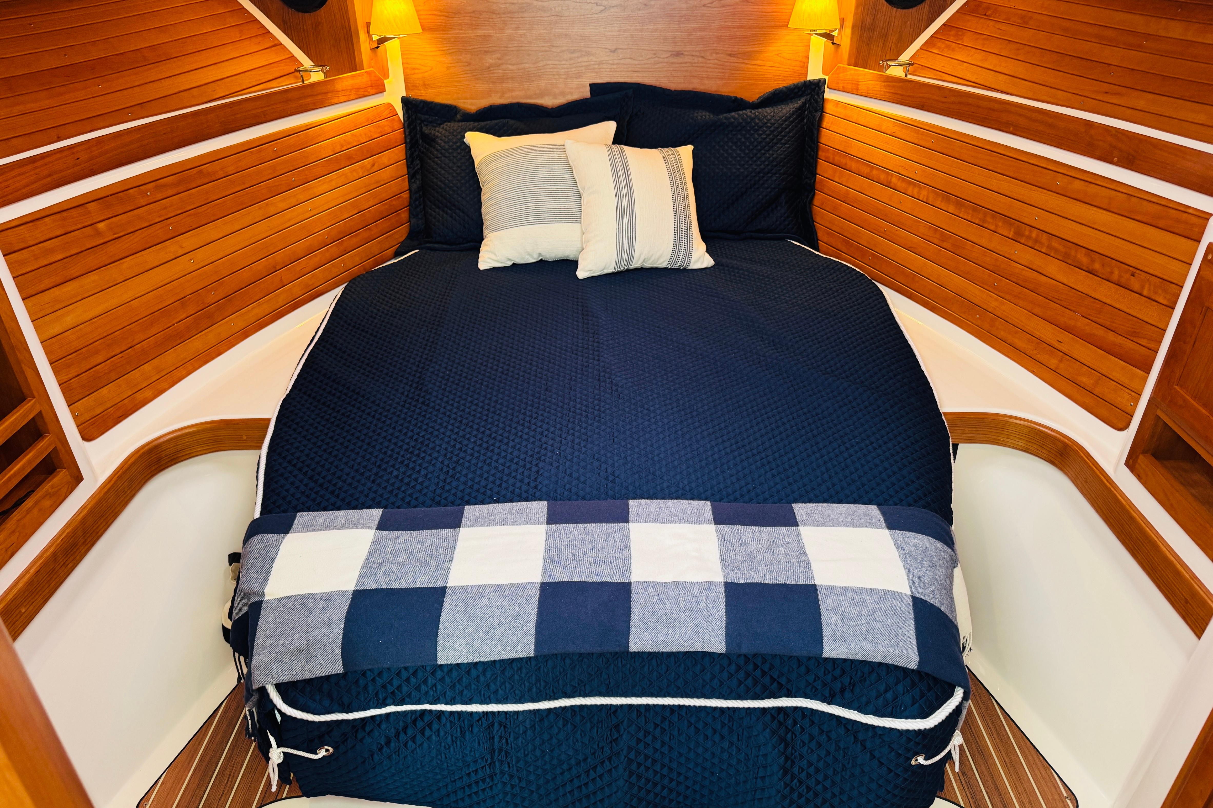 Cozy cabin interior of 2025 Back Cove 34O with navy bedding and wooden accents.