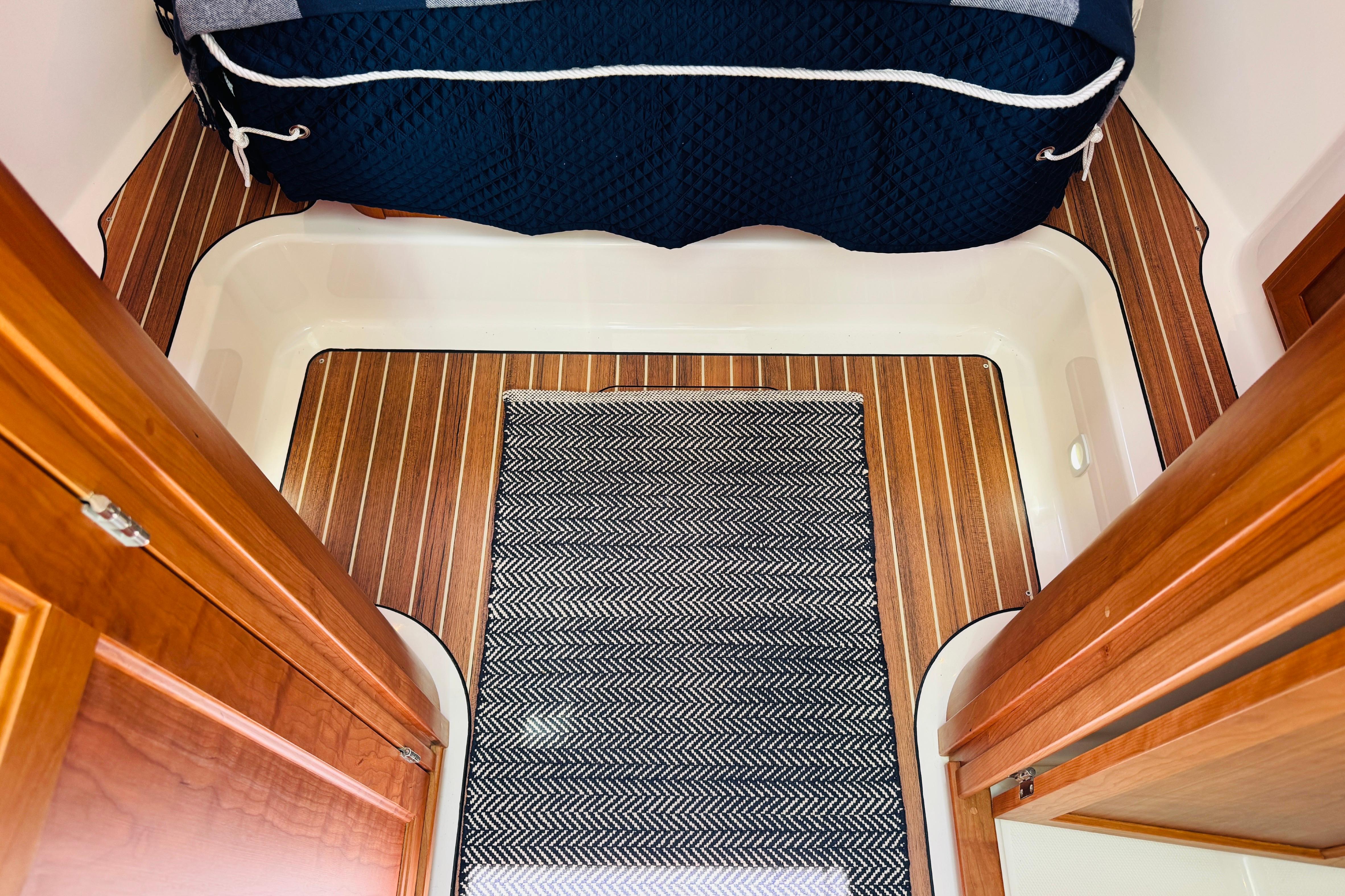 Interior of 2025 Back Cove 34O boat with wood flooring and patterned rug.