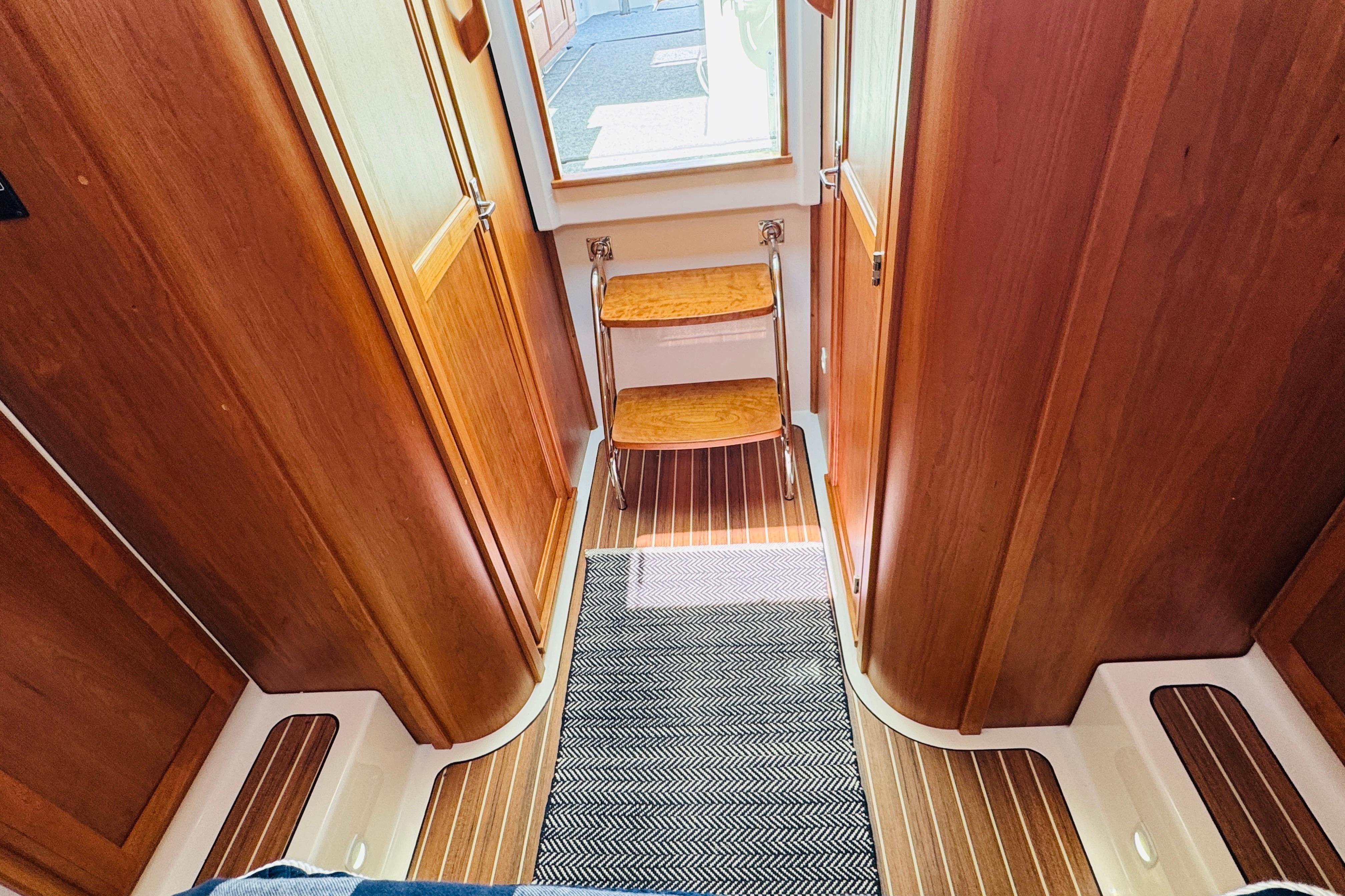 Interior of 2025 Back Cove 34O yacht with wooden finishes and steps.