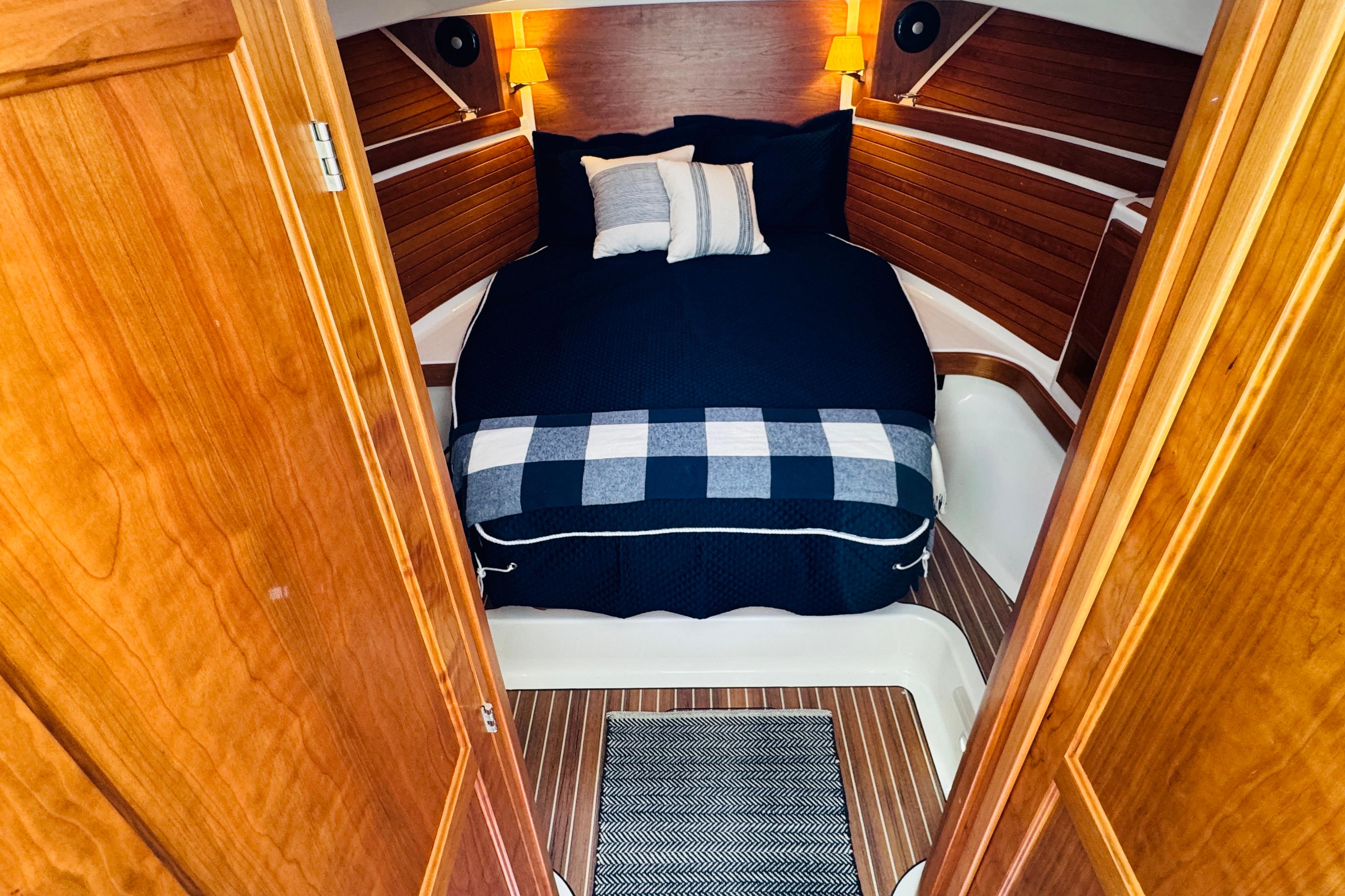 2025 Back Cove 34O cabin interior with cozy bed and wooden accents.
