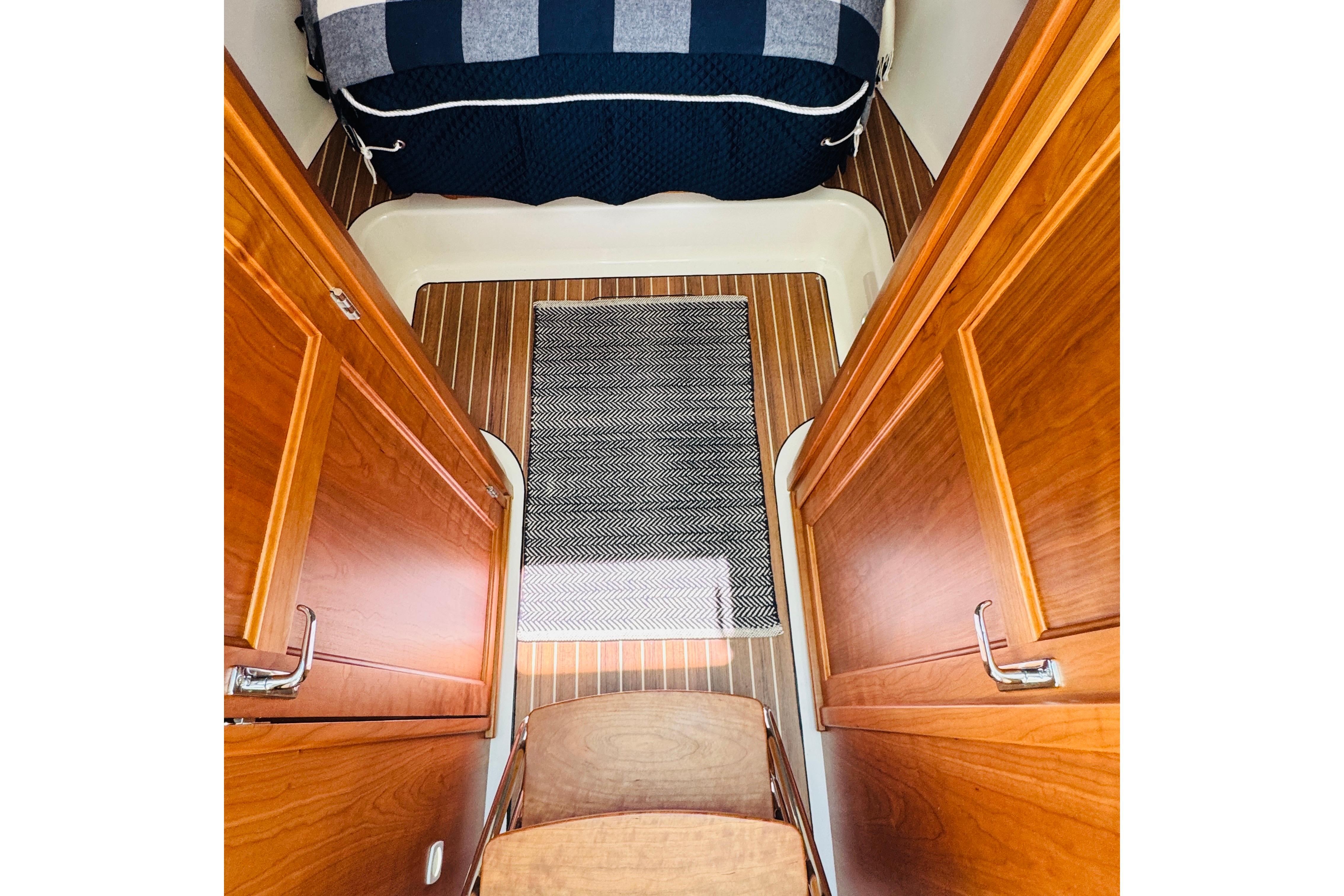 2025 Back Cove 34O cabin interior with wooden finish and striped bedding.